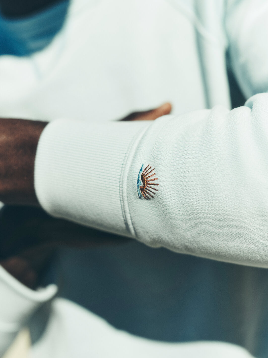 A close up of a Faherty Sun and Waves icon embroidered on sleeve of high standard fleece sweatshirt