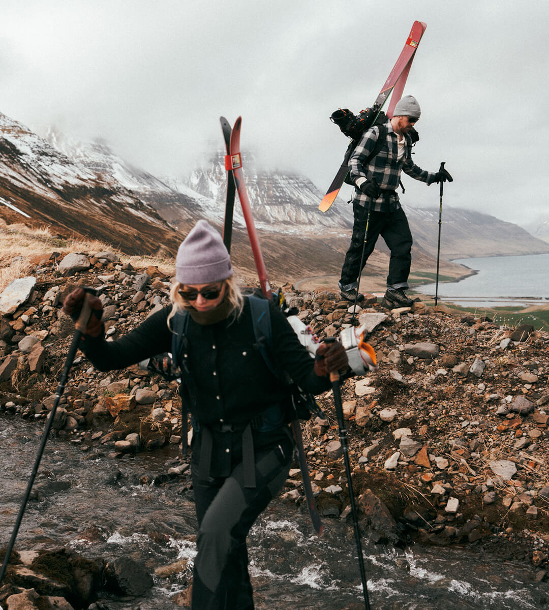 Couple trekking through the Icelandic countryside with cross country skis on their backs