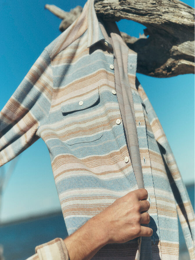 A legend sweater shirt hanging from a driftwood branch on the beach