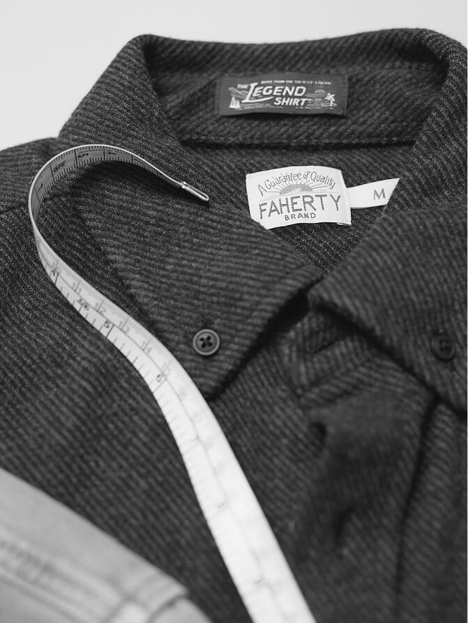 A black and white photo of a tape measure over the collar of a legend sweater shirt