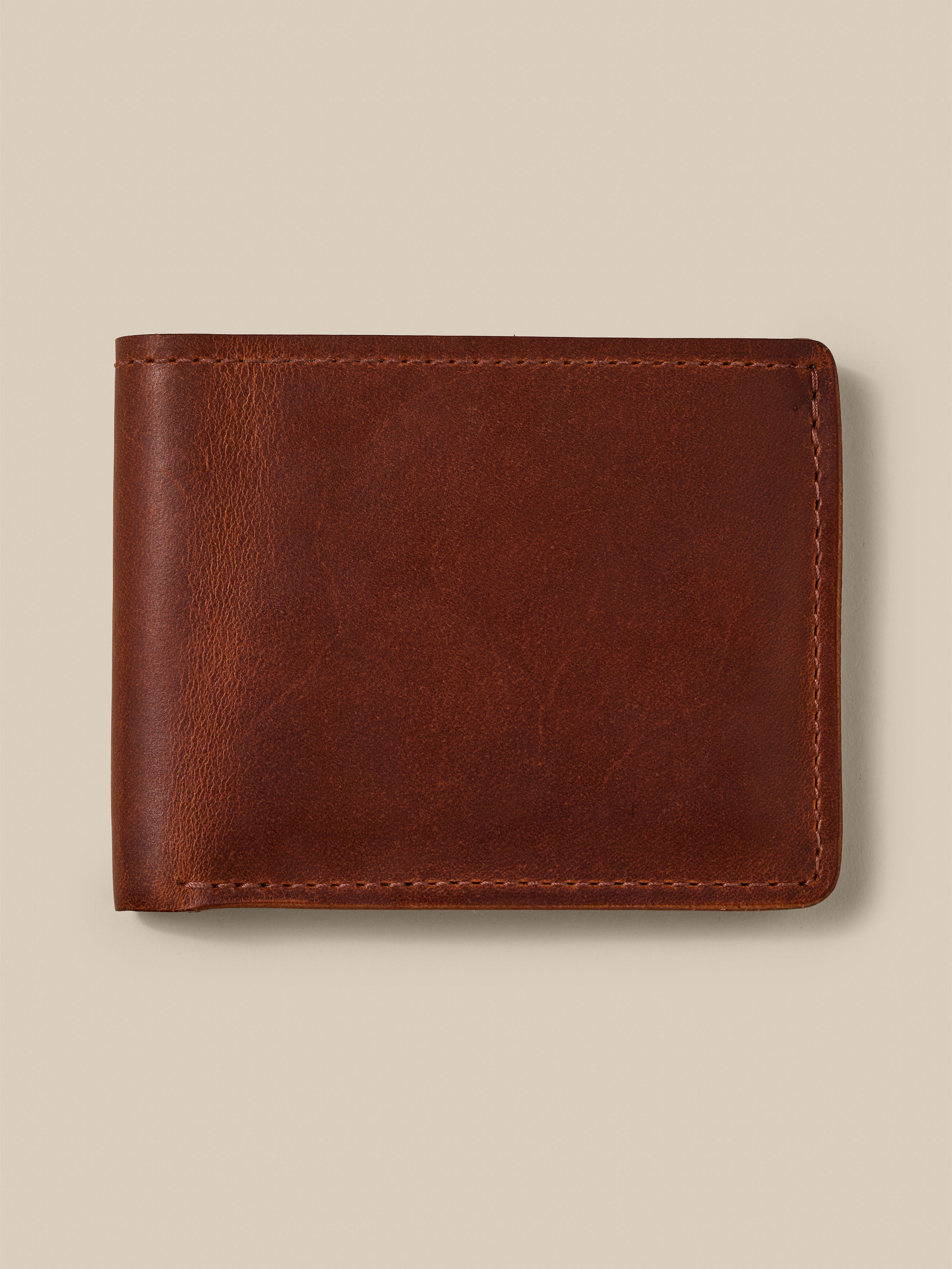 Brown leather wallet against a beige background
