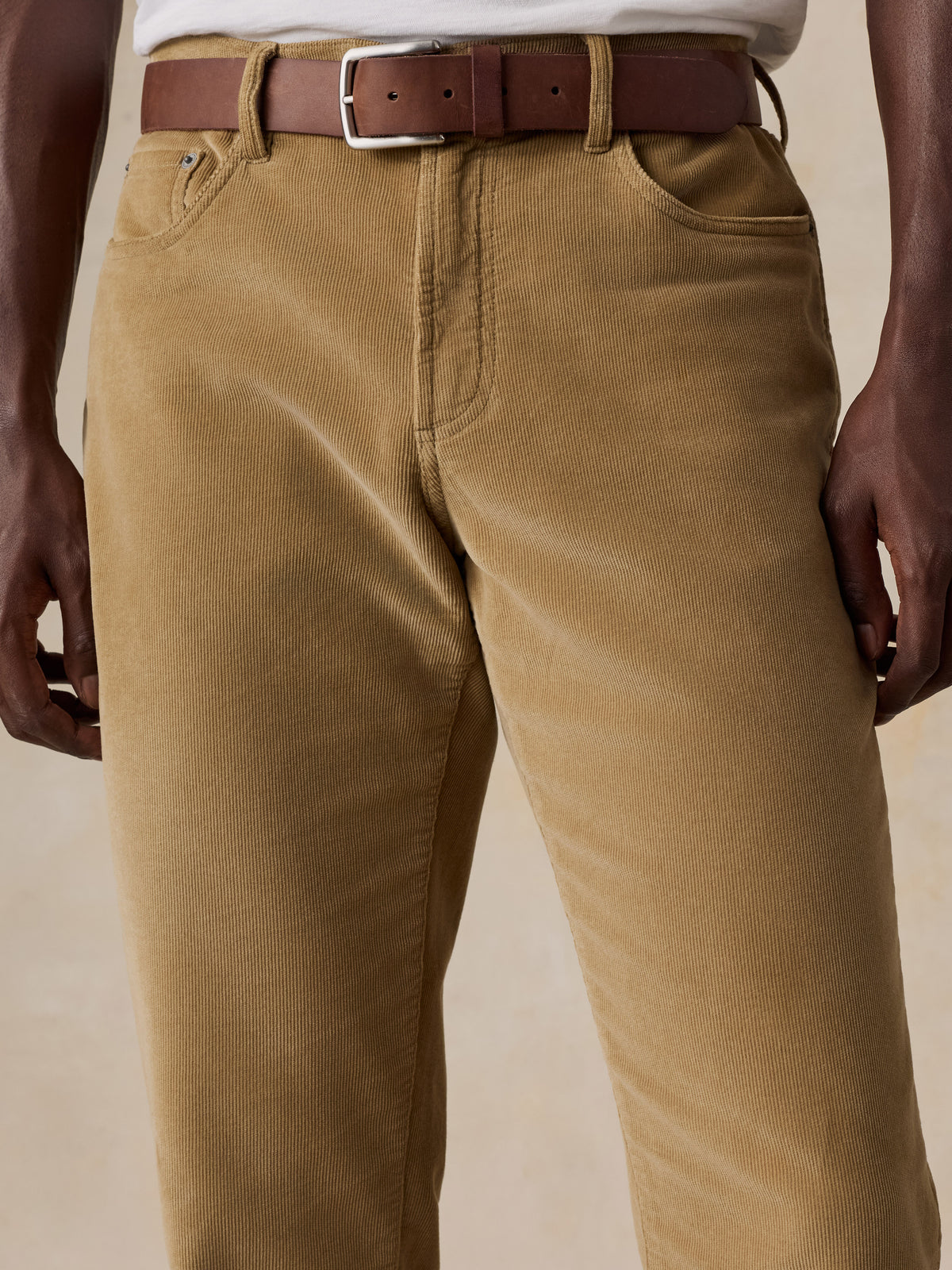 Close up of a man wearing tan corduroy pants and a white tee, image 4 of 5