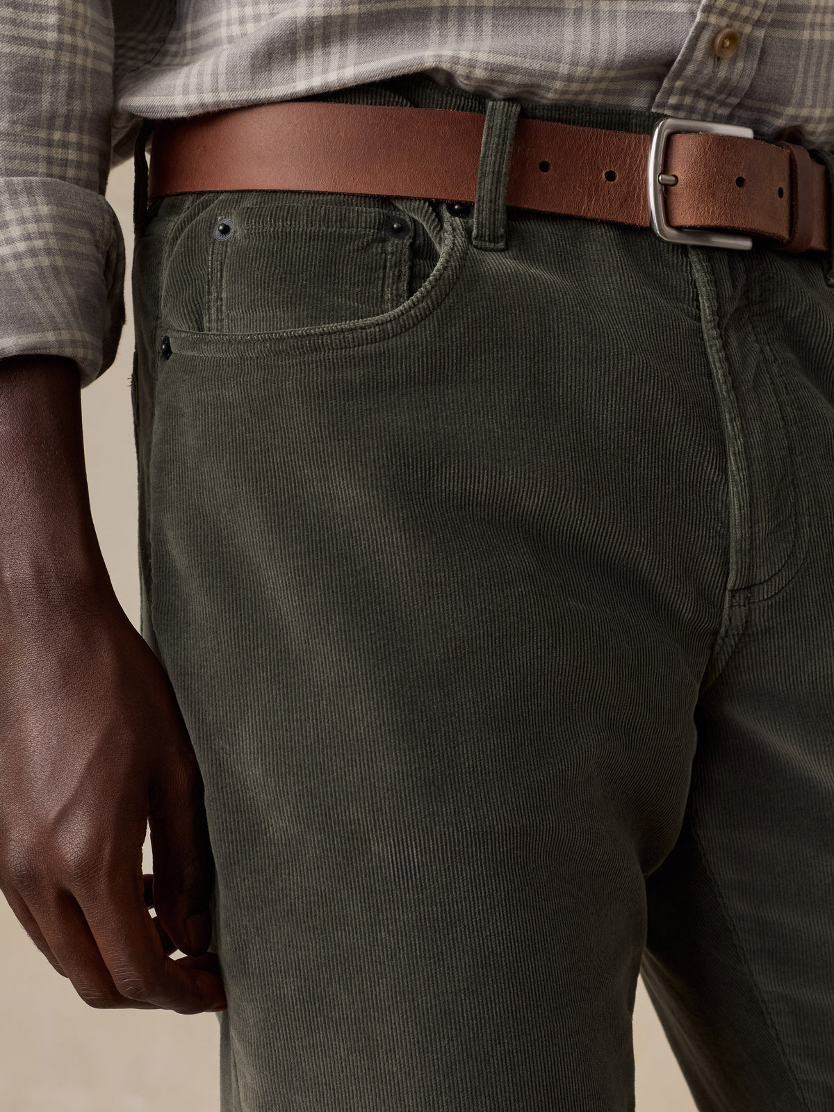 Close up of a man wearing green corduroy pants and a plaid shirt, image 4 of 5