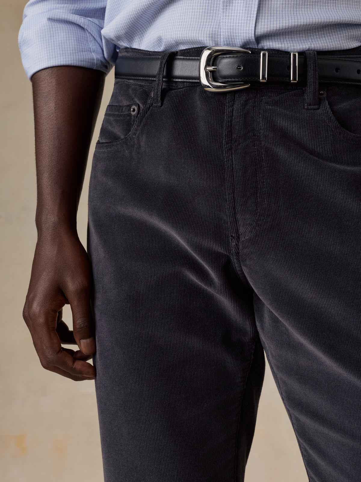 Close up of a man wearing a blue button up shirt and grey corduroy pants, image 4 of 5