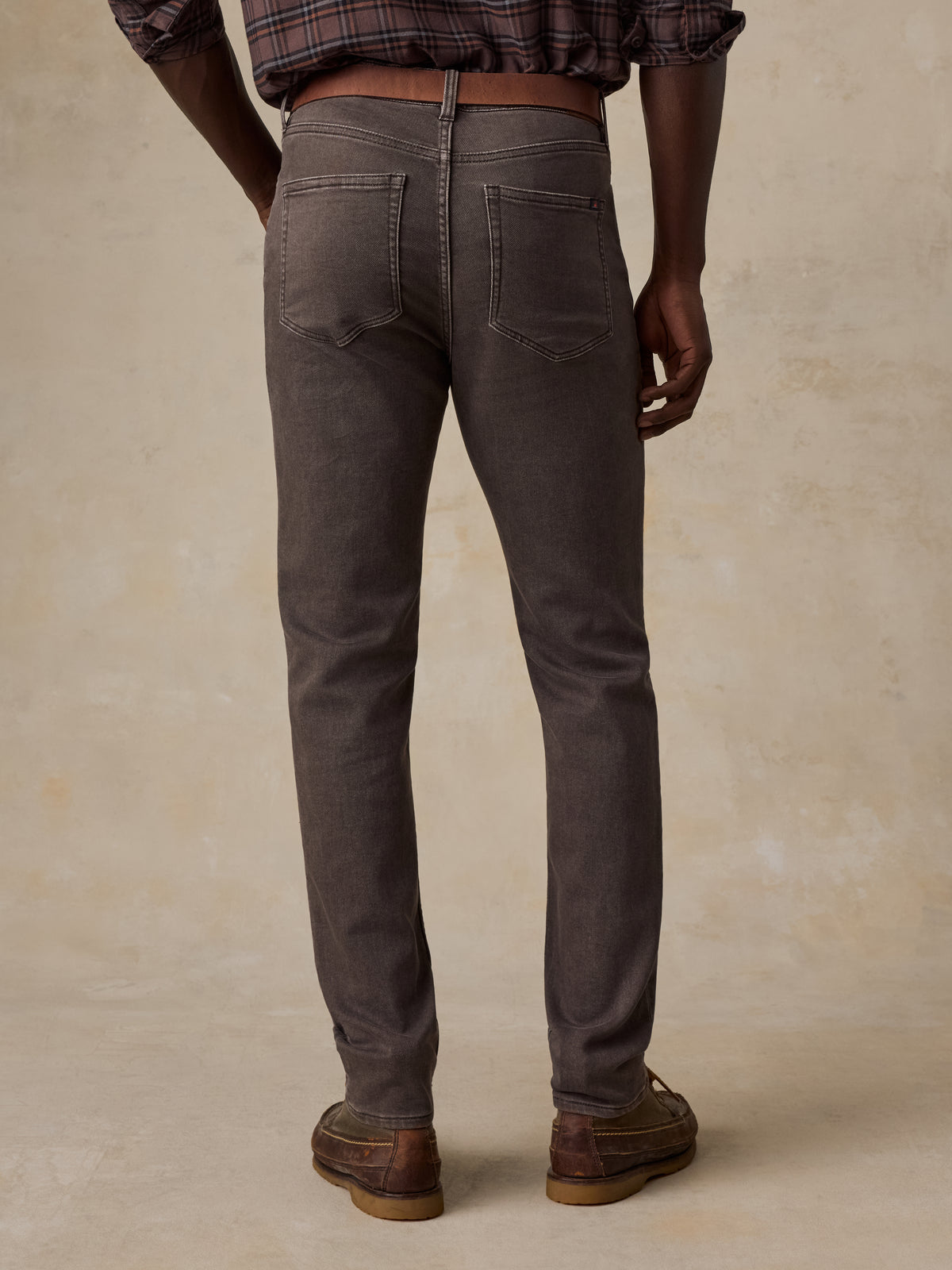 Man viewed from the back wearing a brown plaid shirt and brown pants, image 3 of 5