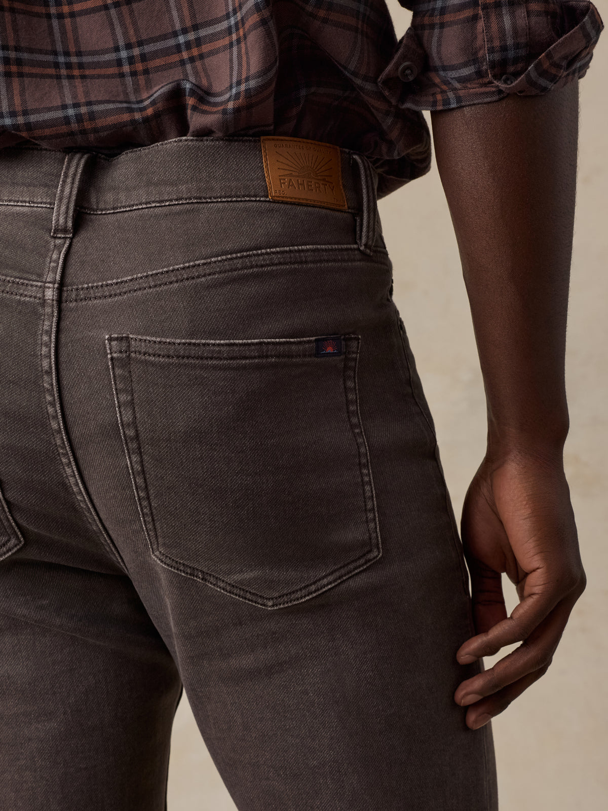 Close up of a man viewed from behind wearing a brown plaid shirt and brown pants, image 5 of 5