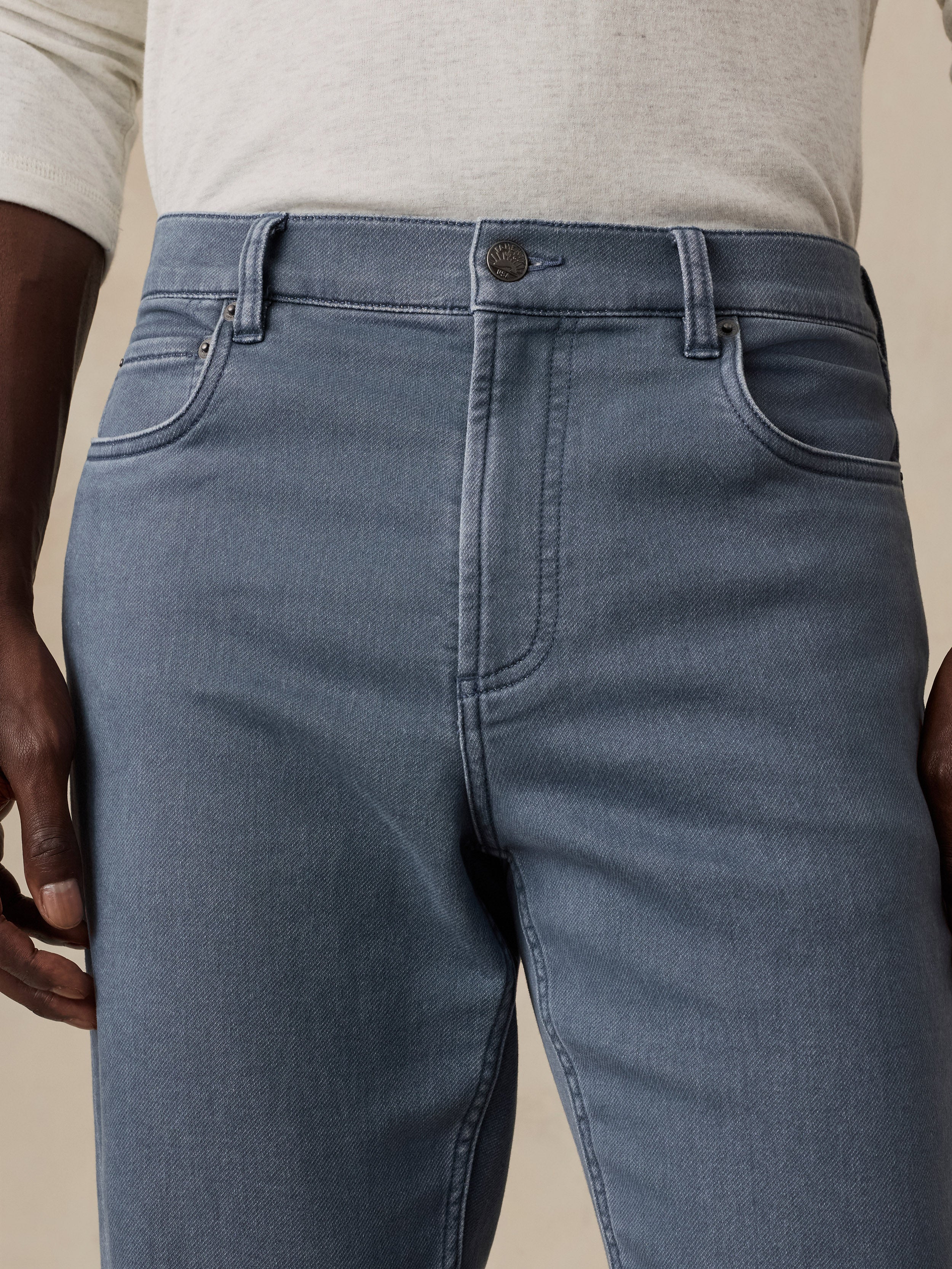 Man wearing blue-gray denim jeans with a light heather gray shirt.