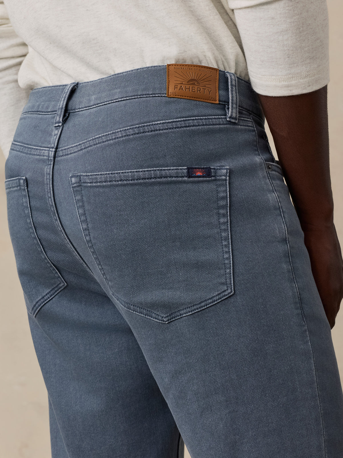 Back view of man in blue denim jeans with waistband leather patch and pocket logo tab.