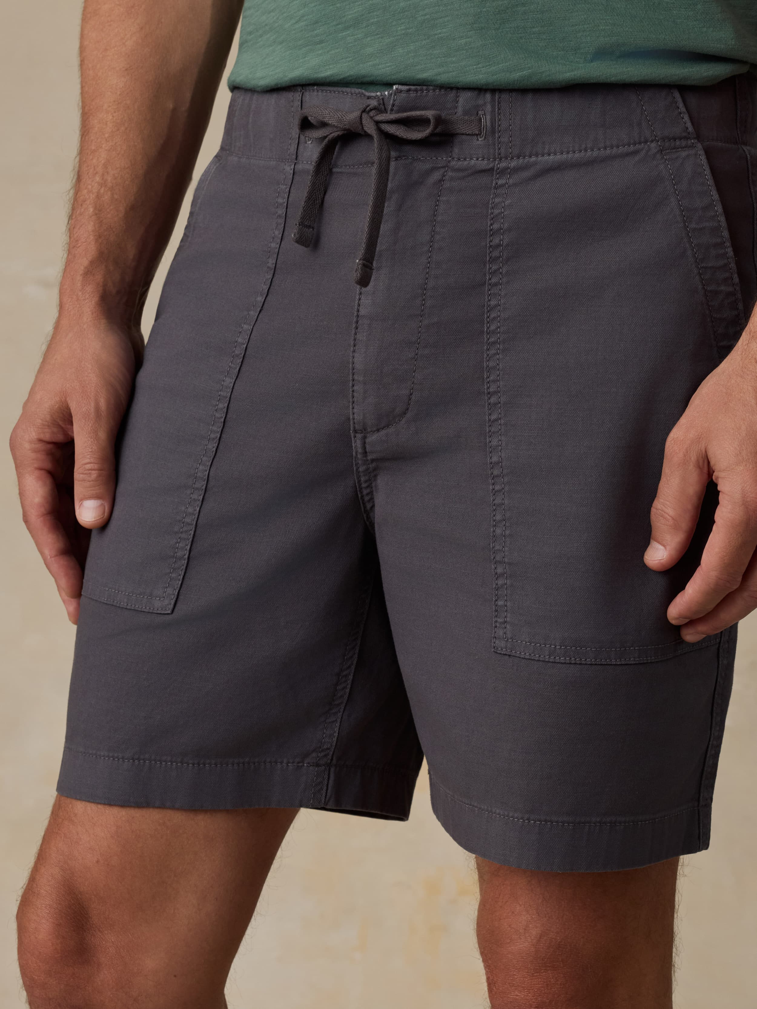 Black shorts worn by a man on a beige background