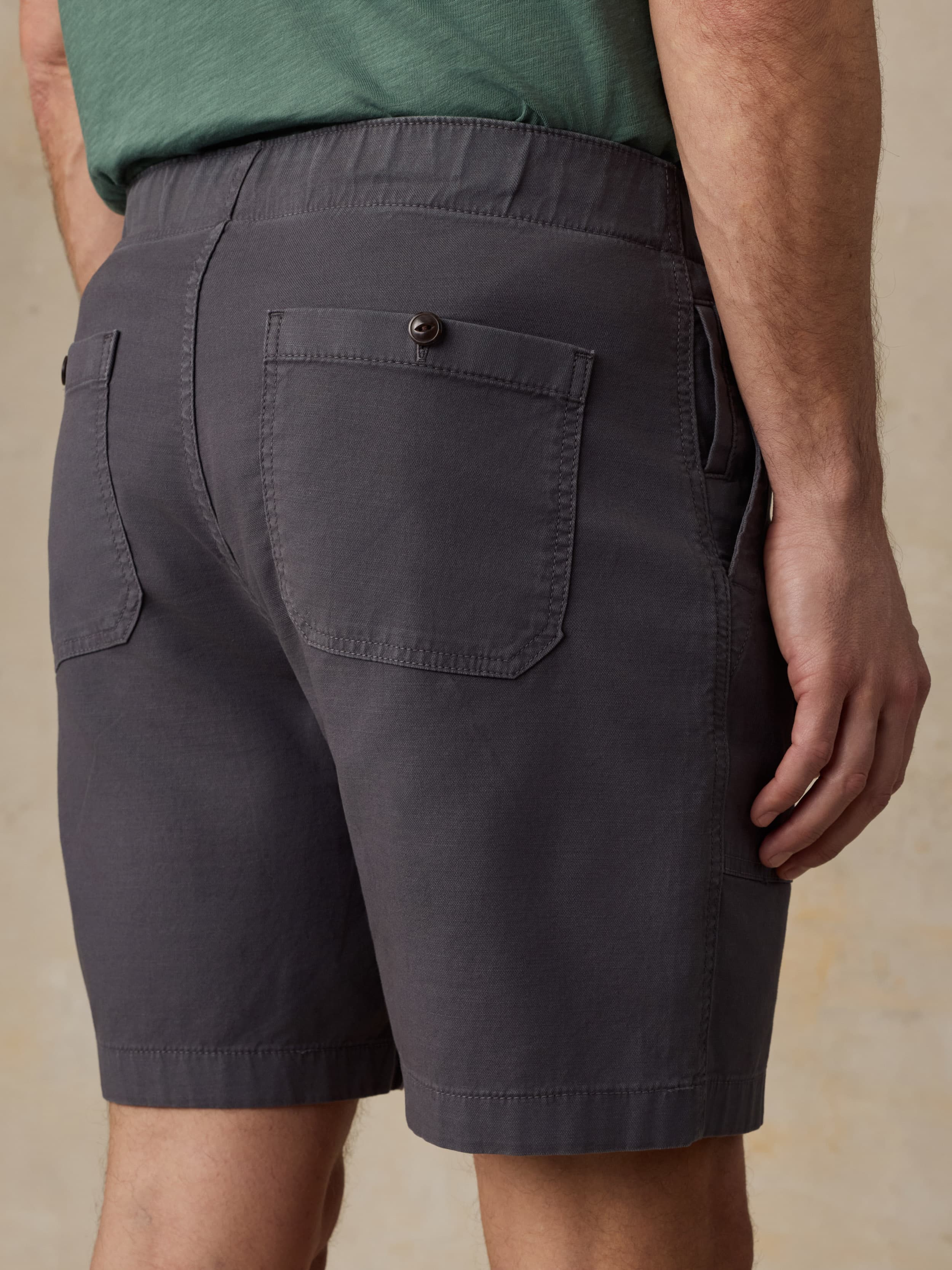Person wearing black shorts with a beige background