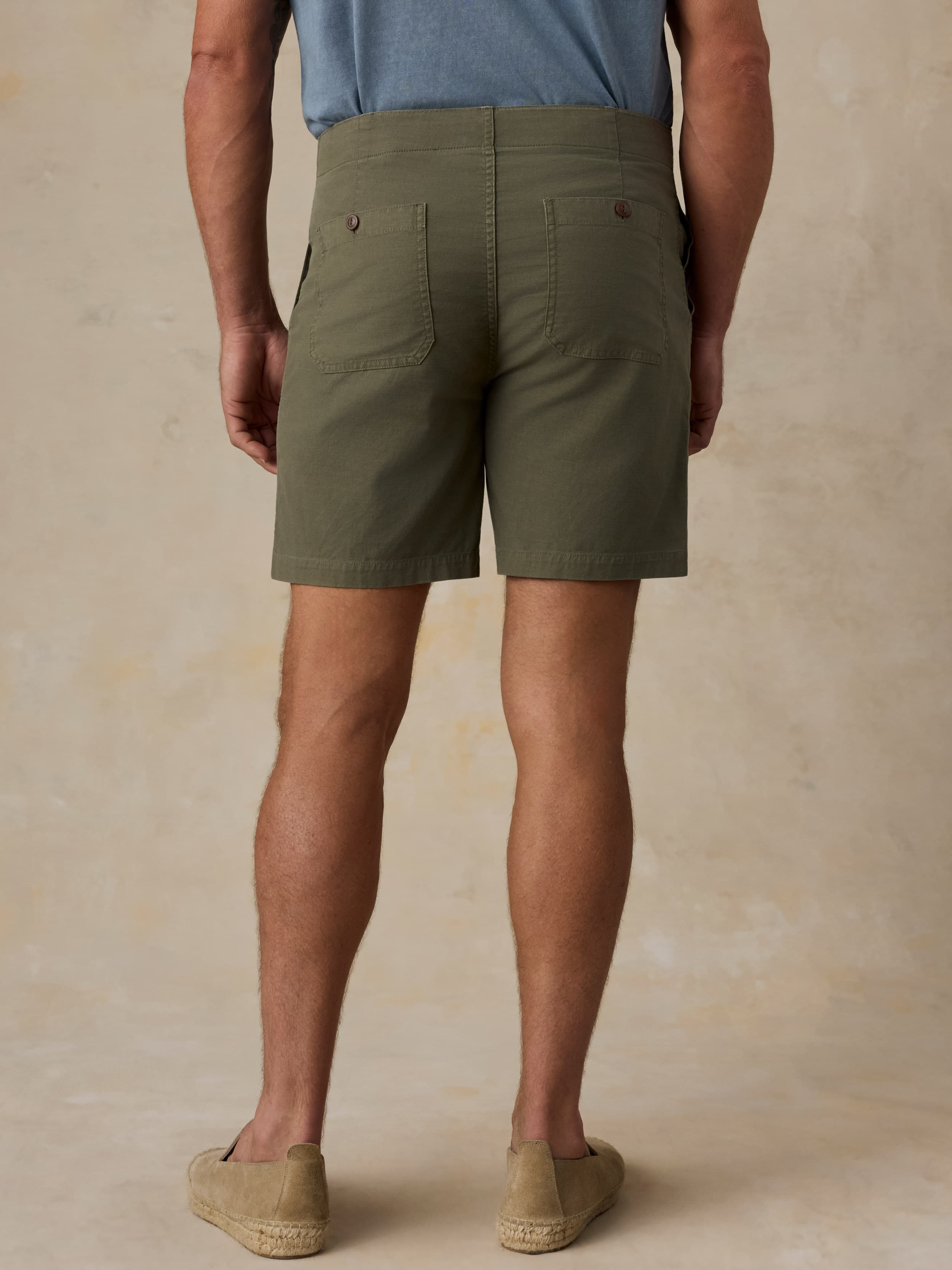 Man wearing olive green shorts on a beige background
