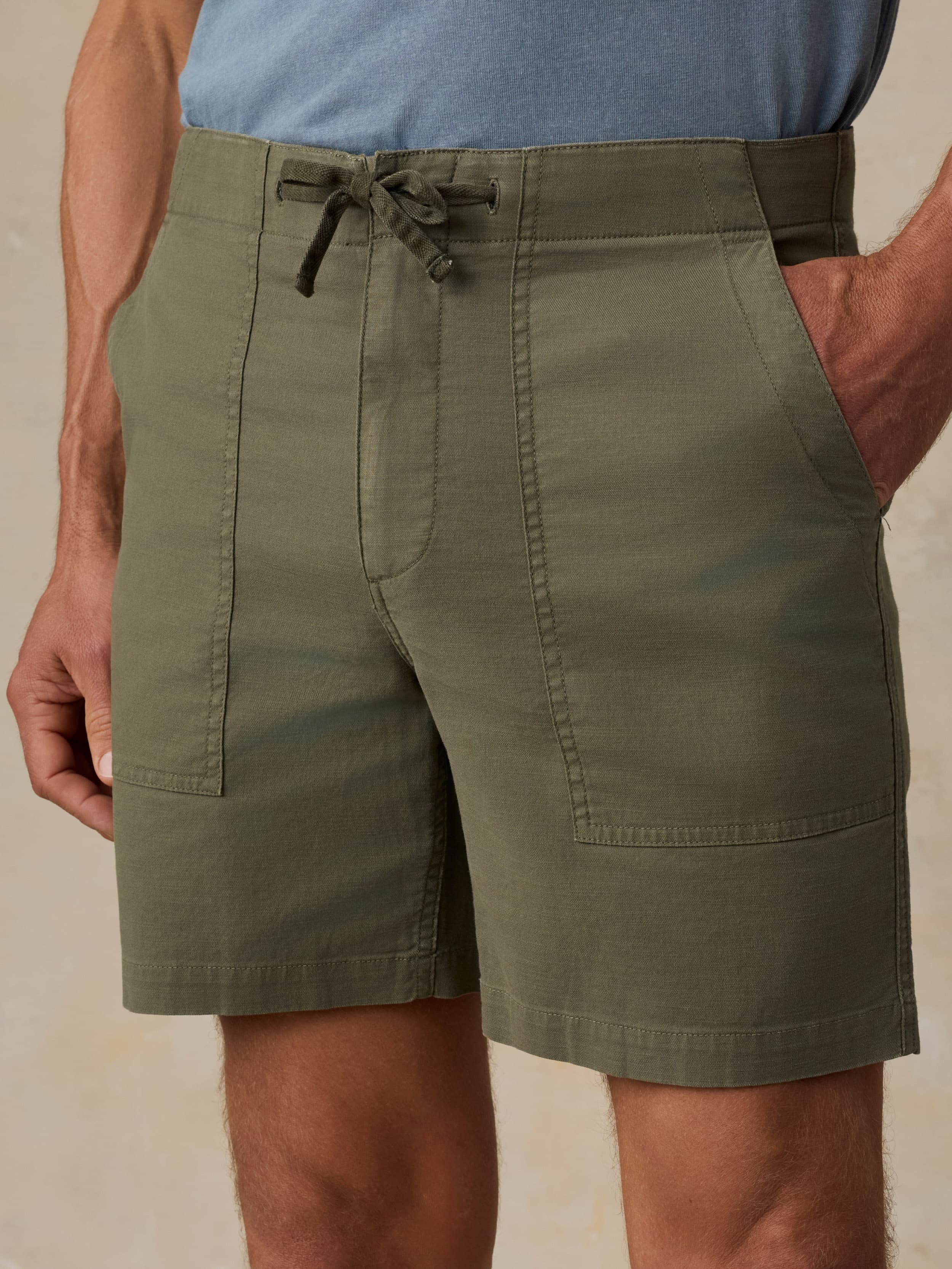 Man wearing olive green shorts with a beige background