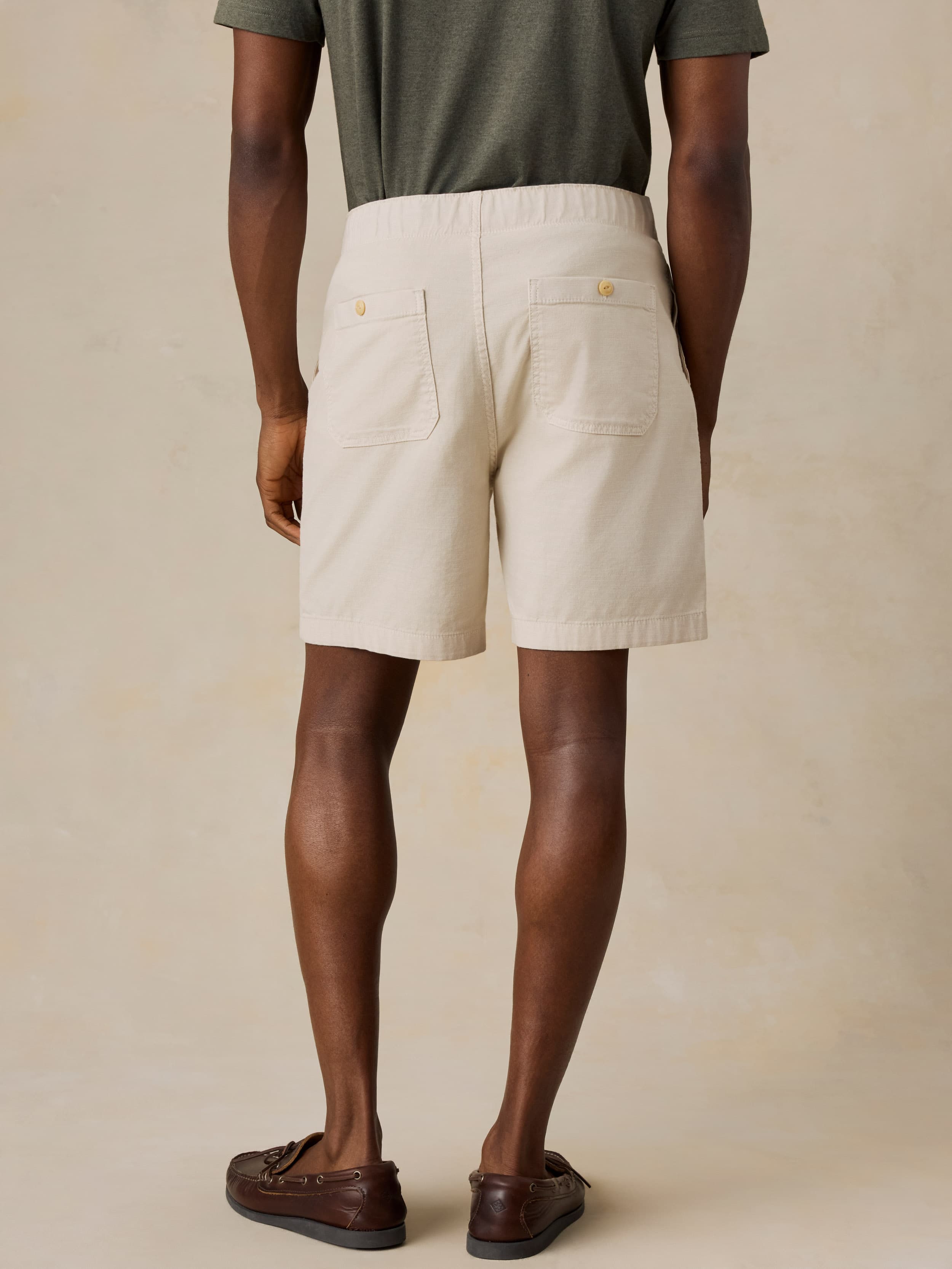 Man wearing beige shorts on a plain background