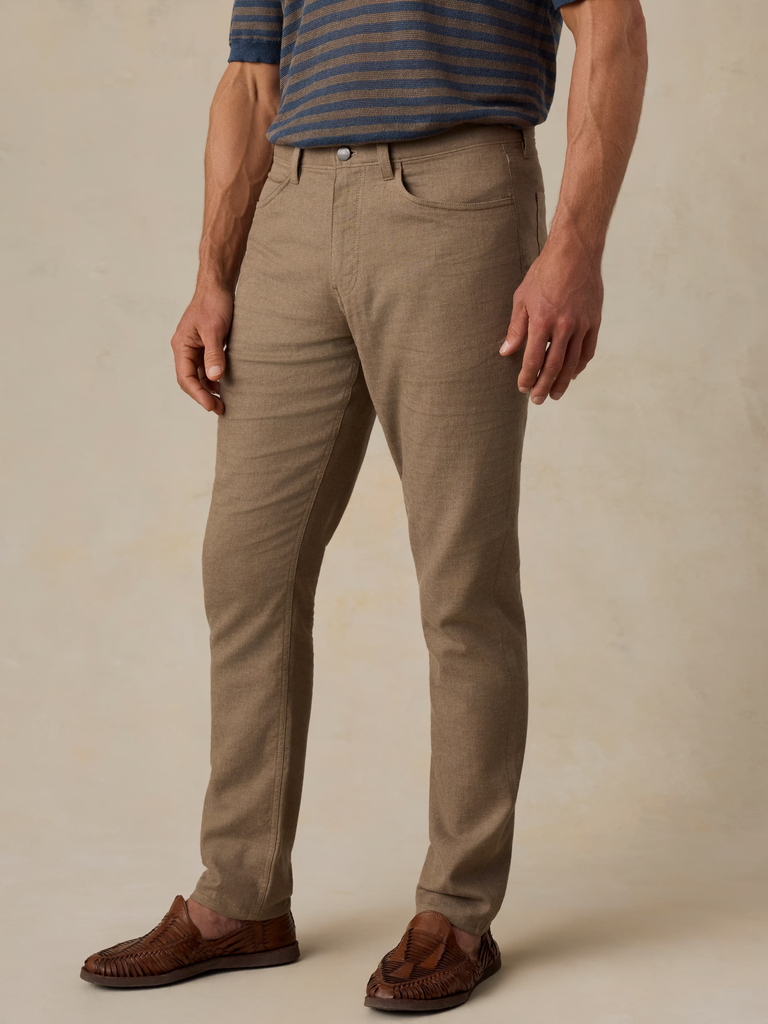 Man wearing green pants and a striped tee against a beige background