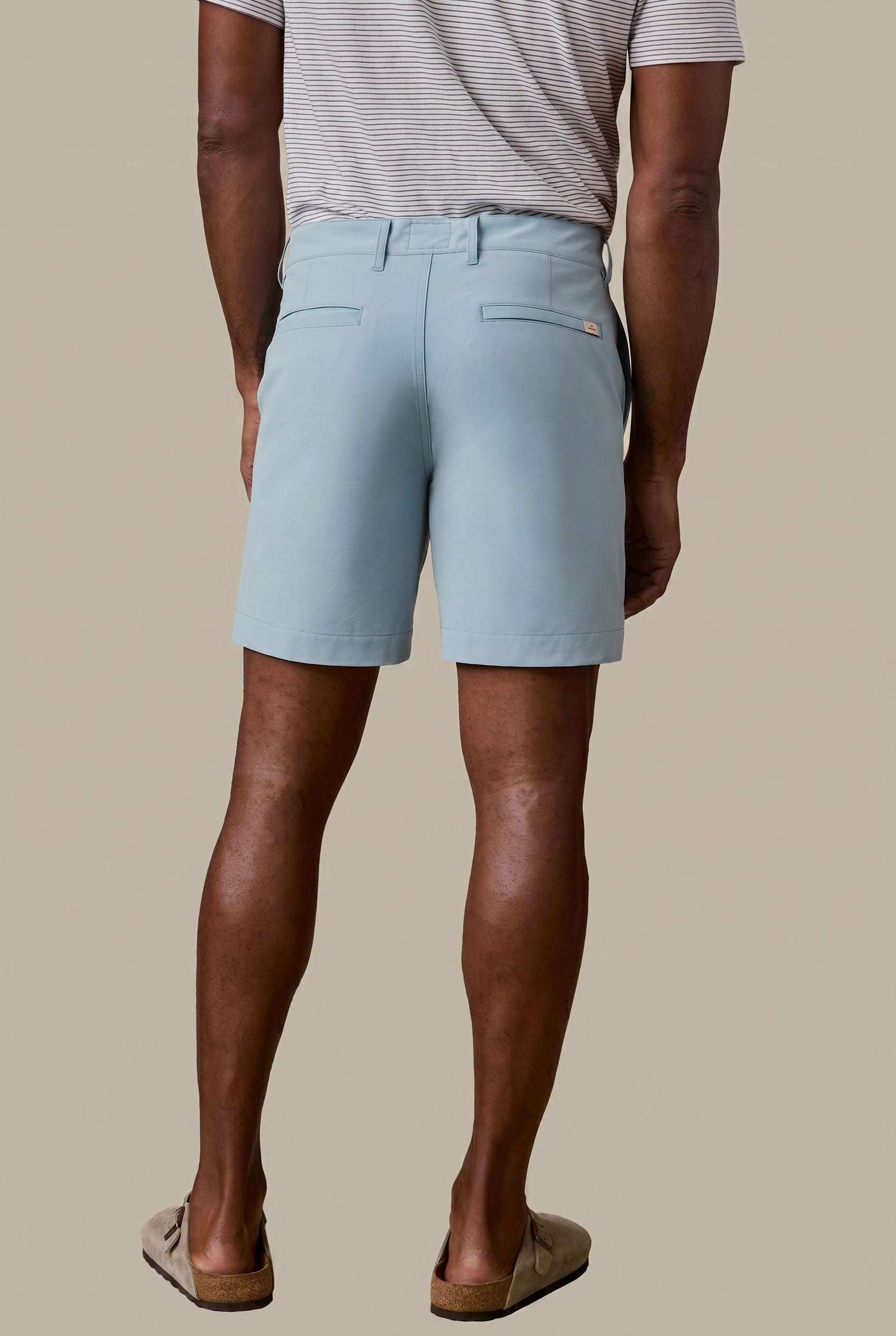 Man wearing light blue shorts on a beige background