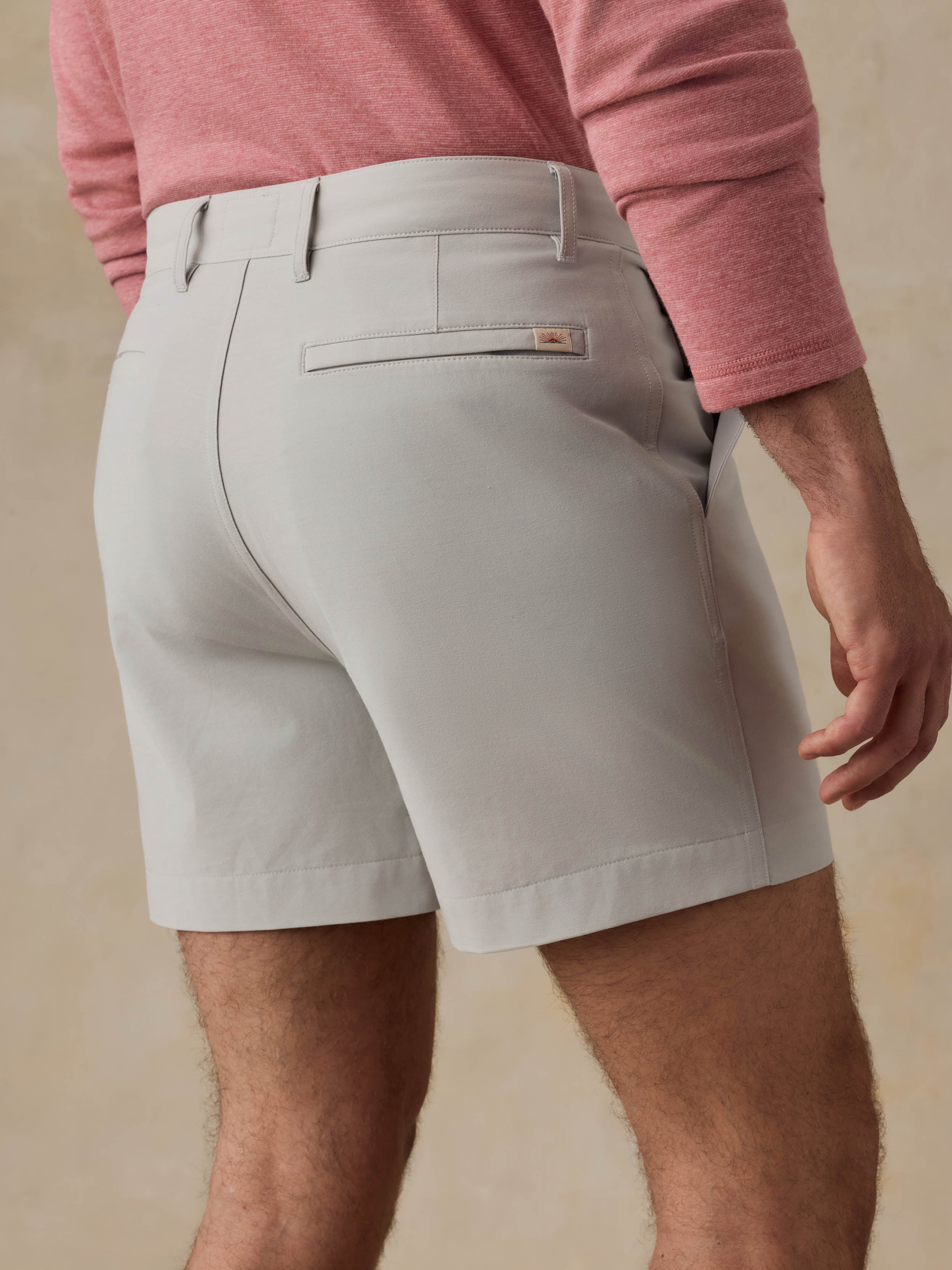 Man is wearing grey shorts and a red crewneck against a beige background
