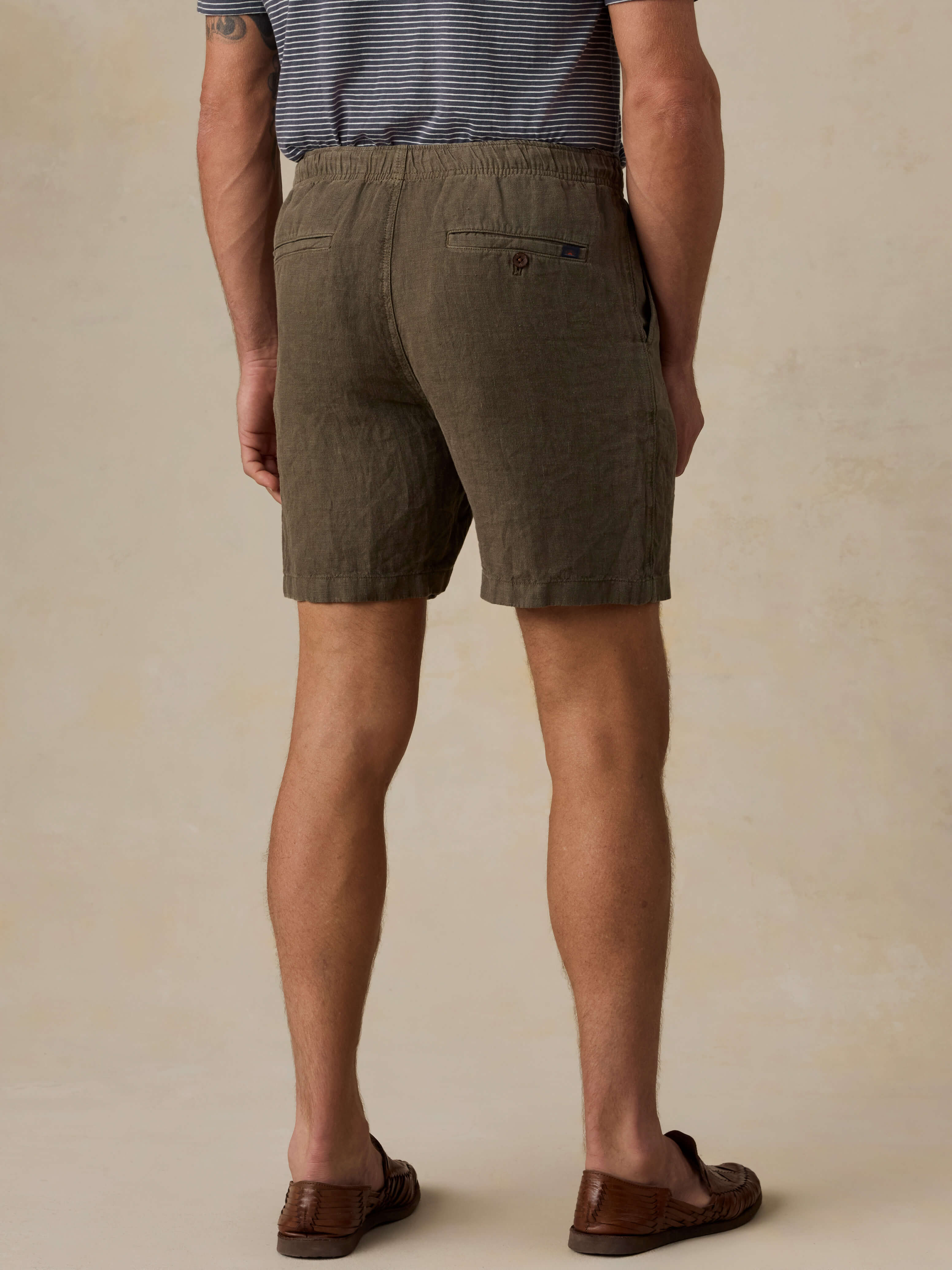 Man wearing olive green shorts on a beige background