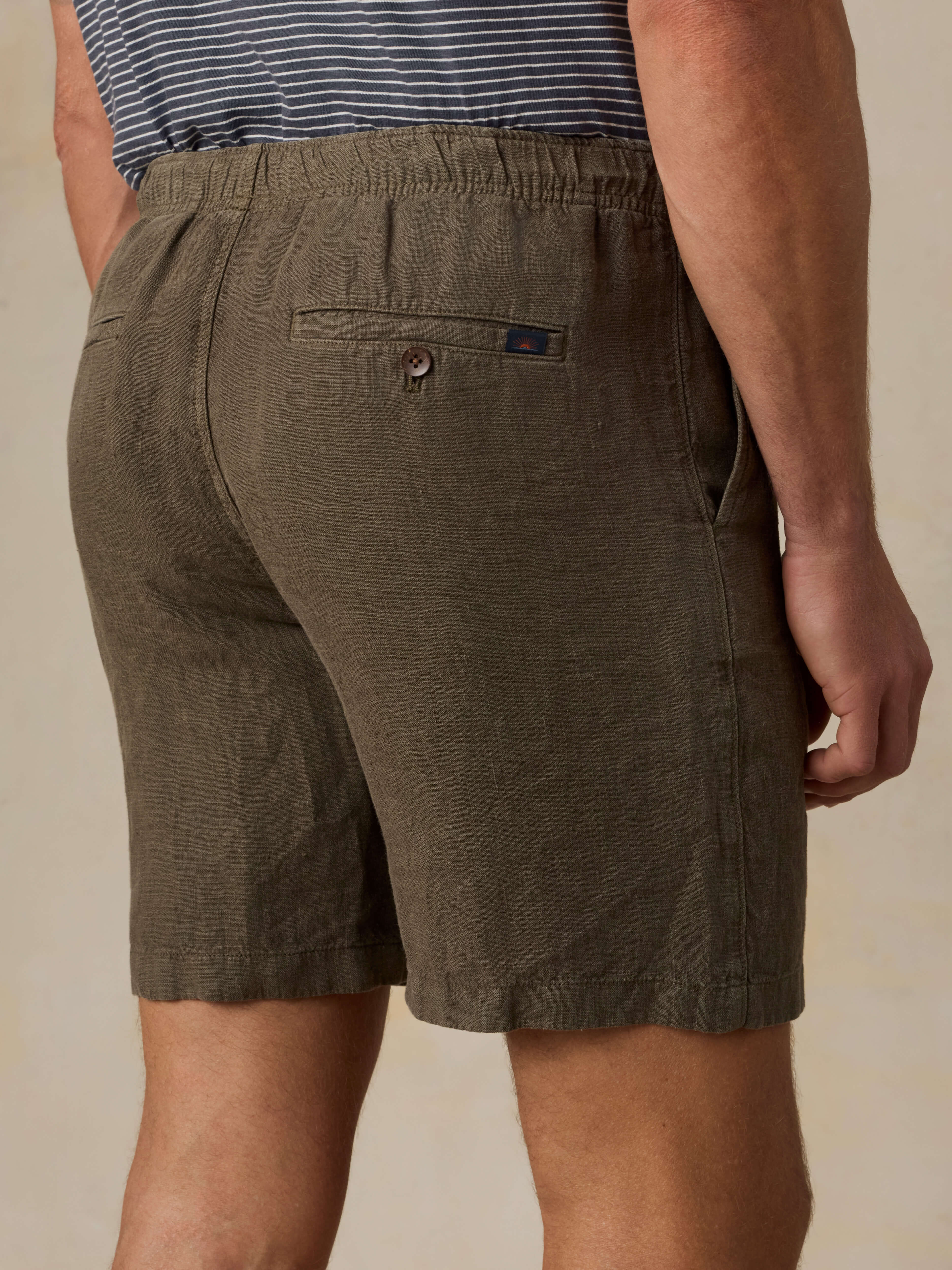 Man wearing brown shorts with a visible Faherty brand logo on a beige background