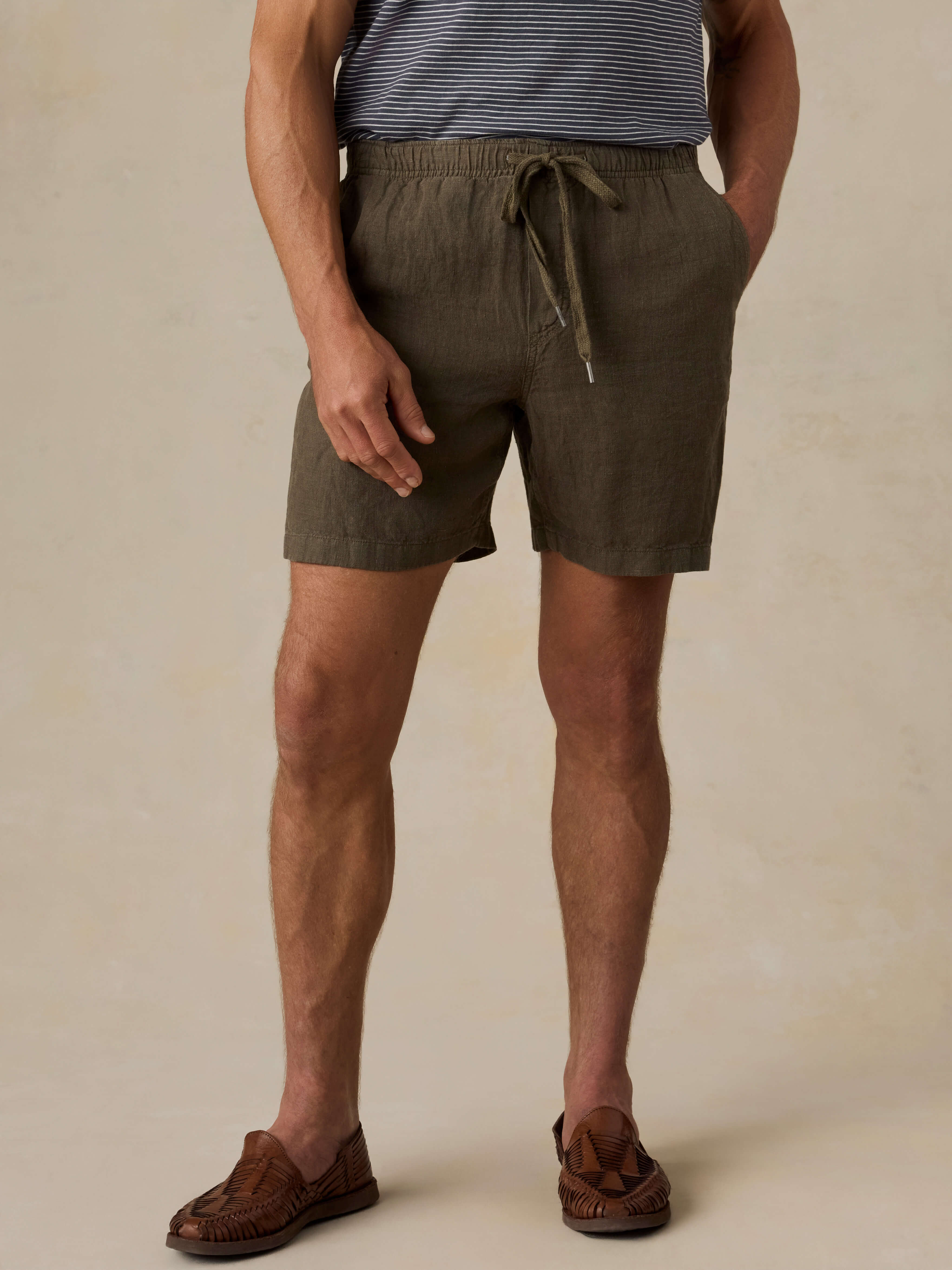 Man wearing olive green shorts on a beige background