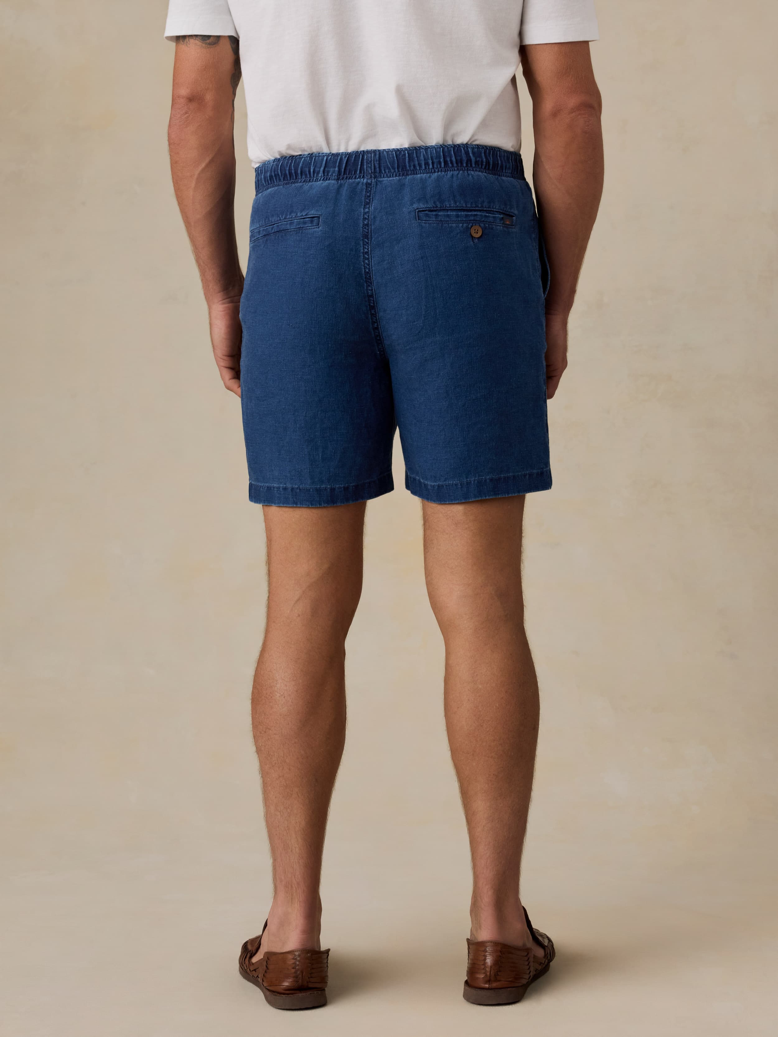 Man wearing navy linen shorts against a beige background