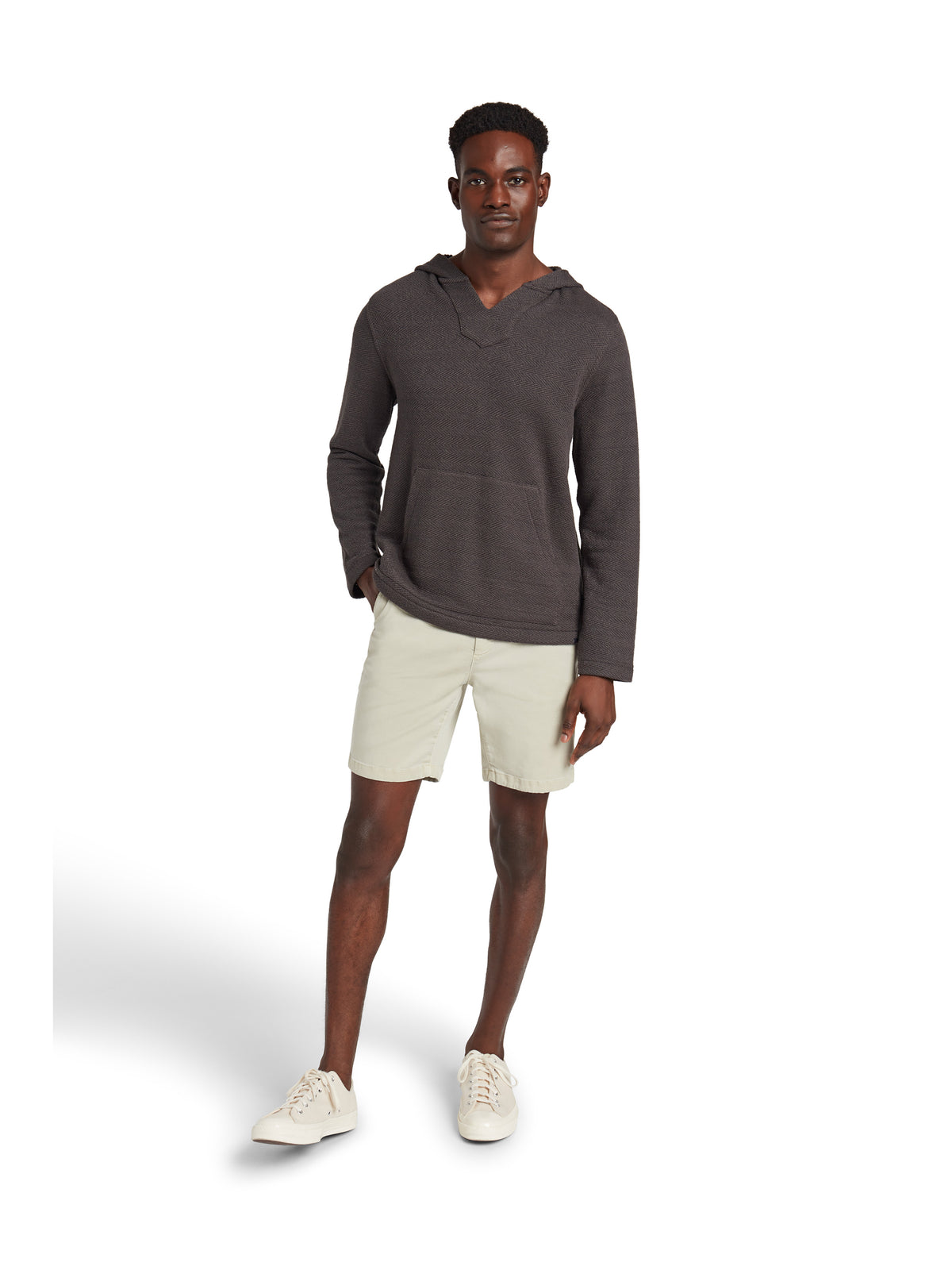A man wearing a black hoodie, beige shorts, and sneakers, image 2 of 3