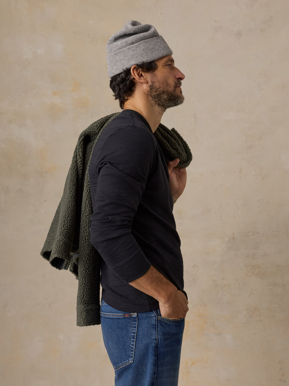 A man wearing a black crewneck and a beanie, image 5 of 6
