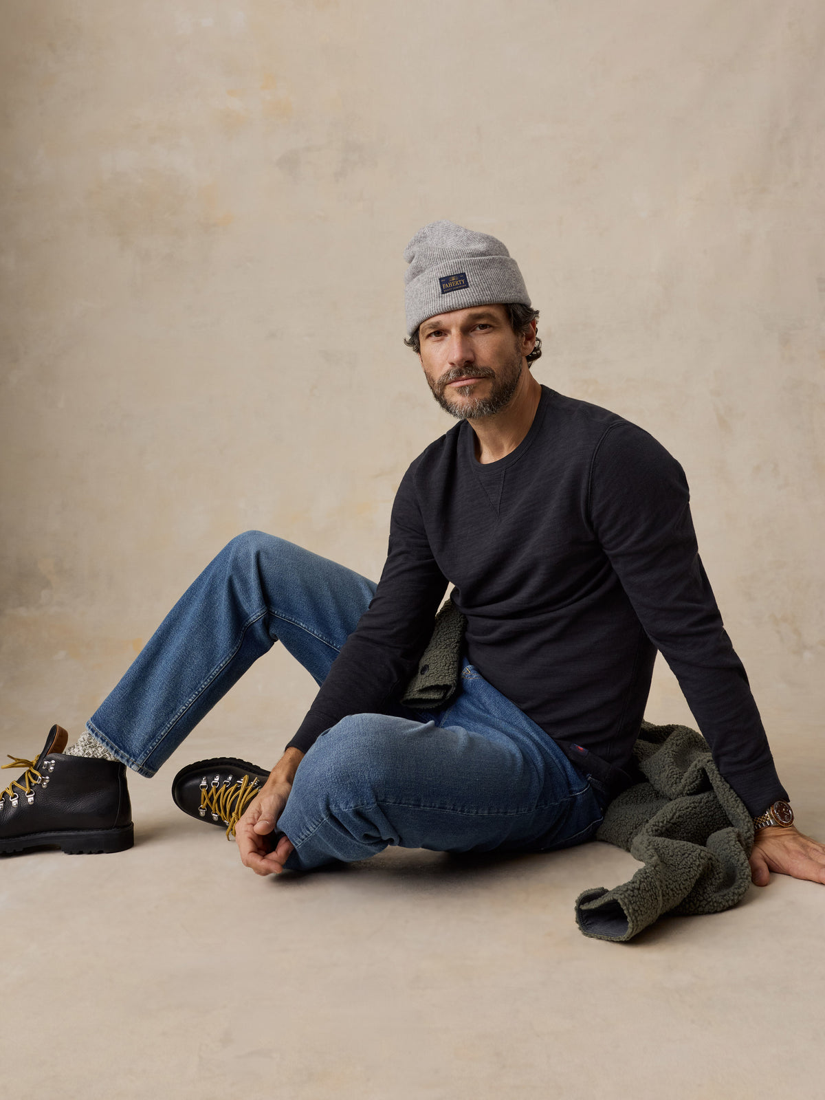 A man wearing a black crewneck and jeans, image 4 of 6