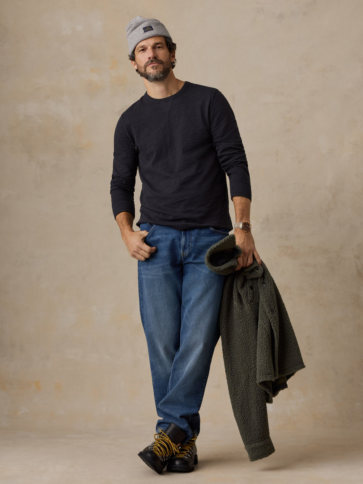 A man wearing a black crewneck and jeans, image 2 of 6