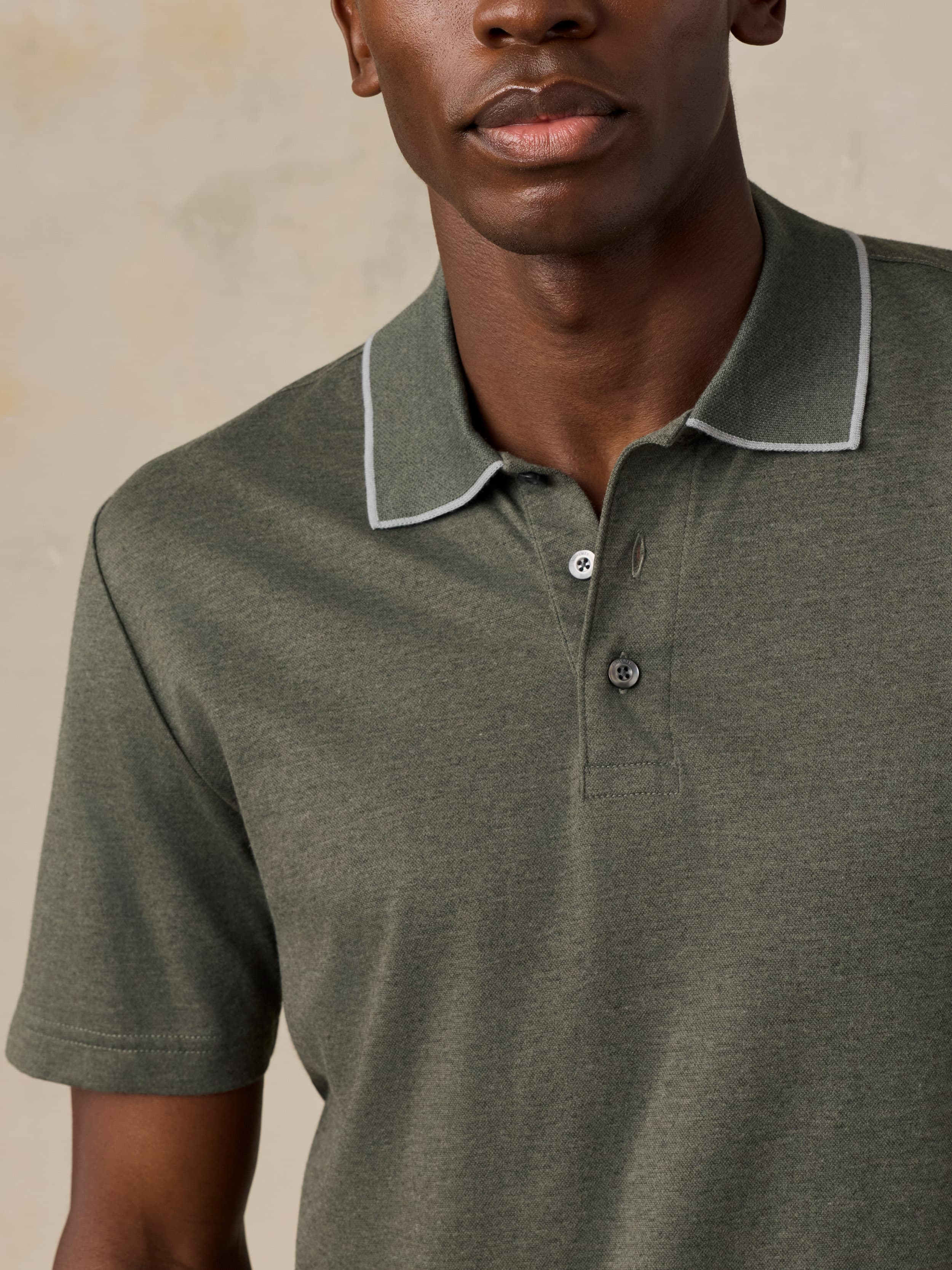 Man wearing a green polo against a beige background