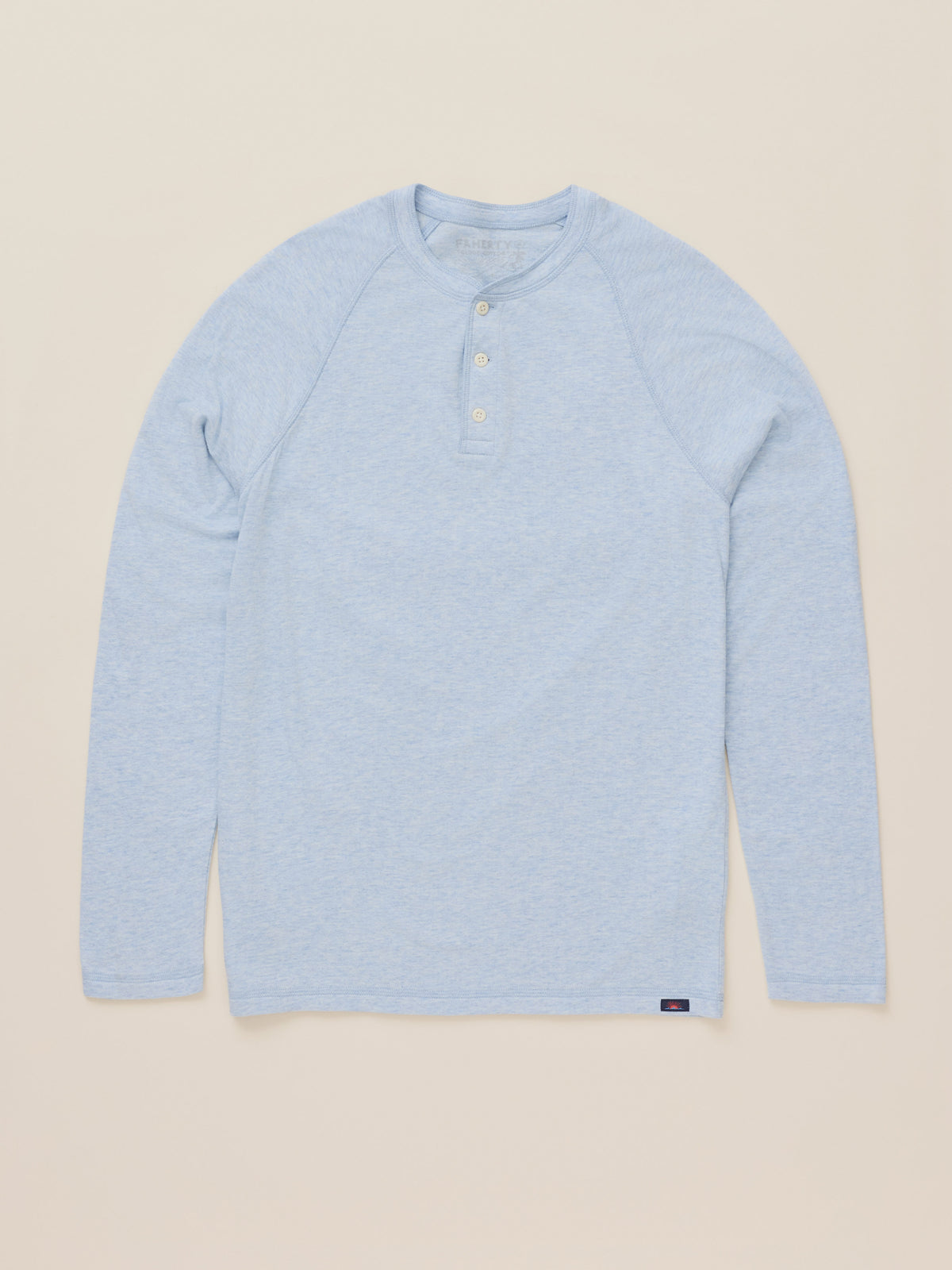 A light blue heather long-sleeve henley shirt with a three-button placket, laid flat against a solid beige background., image 8 of 9