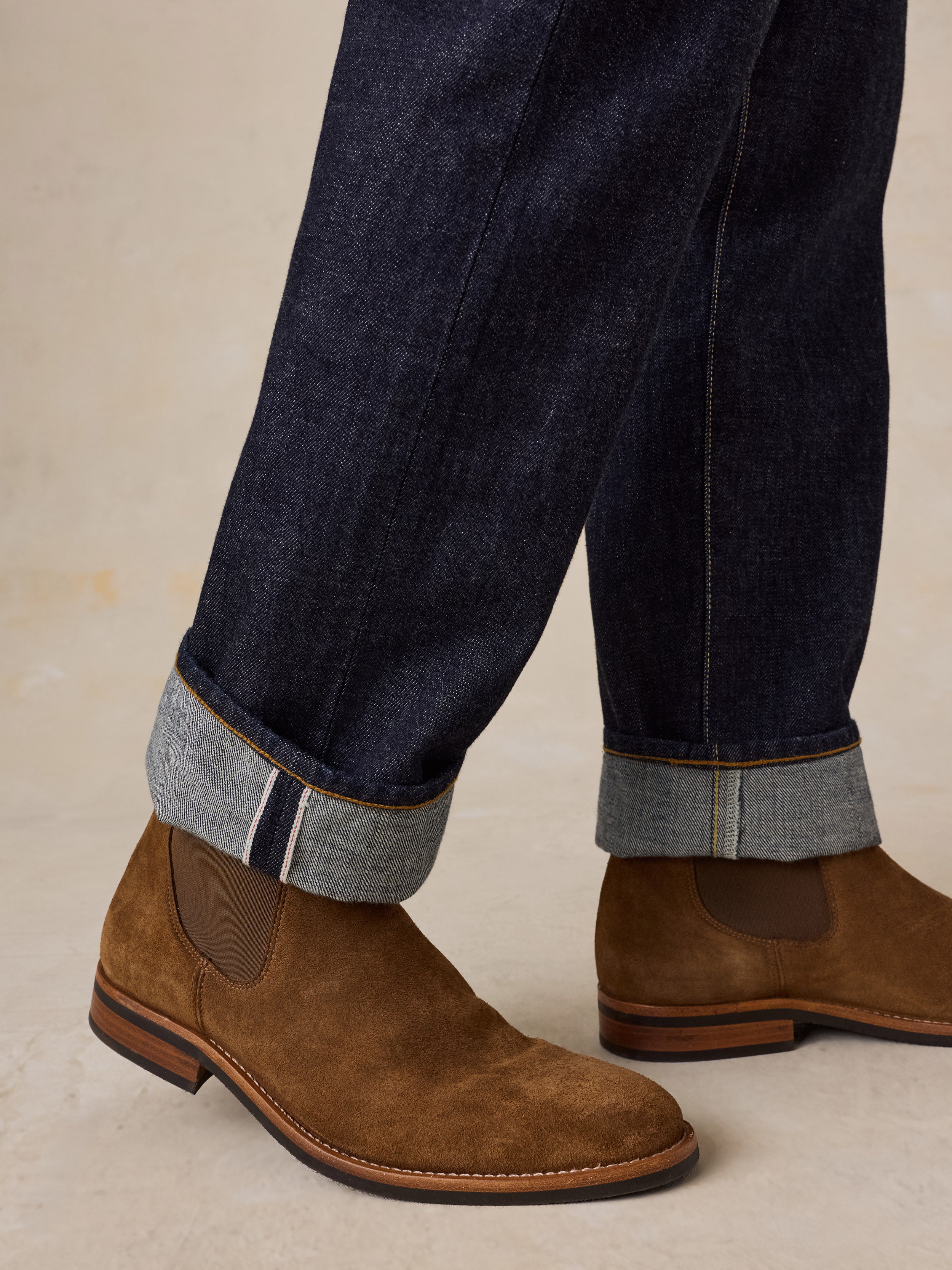 A man wearing brown suede boots with blue jeans