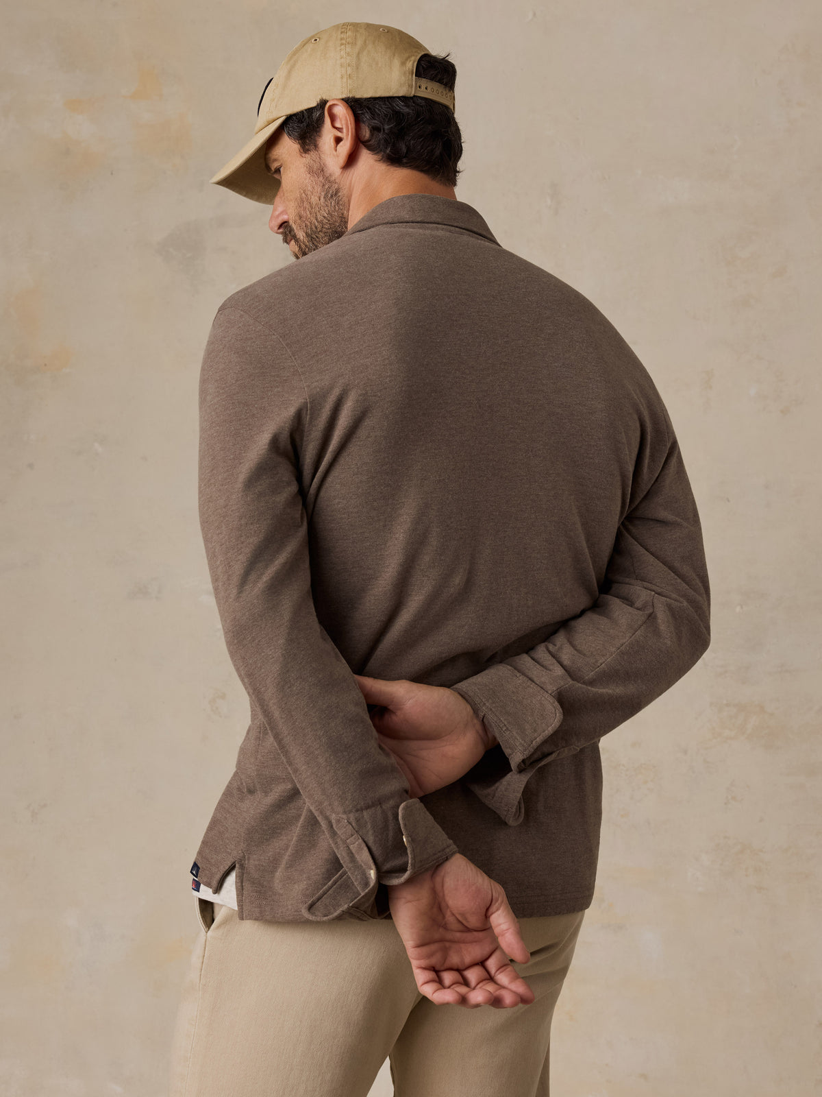 A man viewed from the back wearing a brown polo shirt and beige chino pants, image 2 of 6