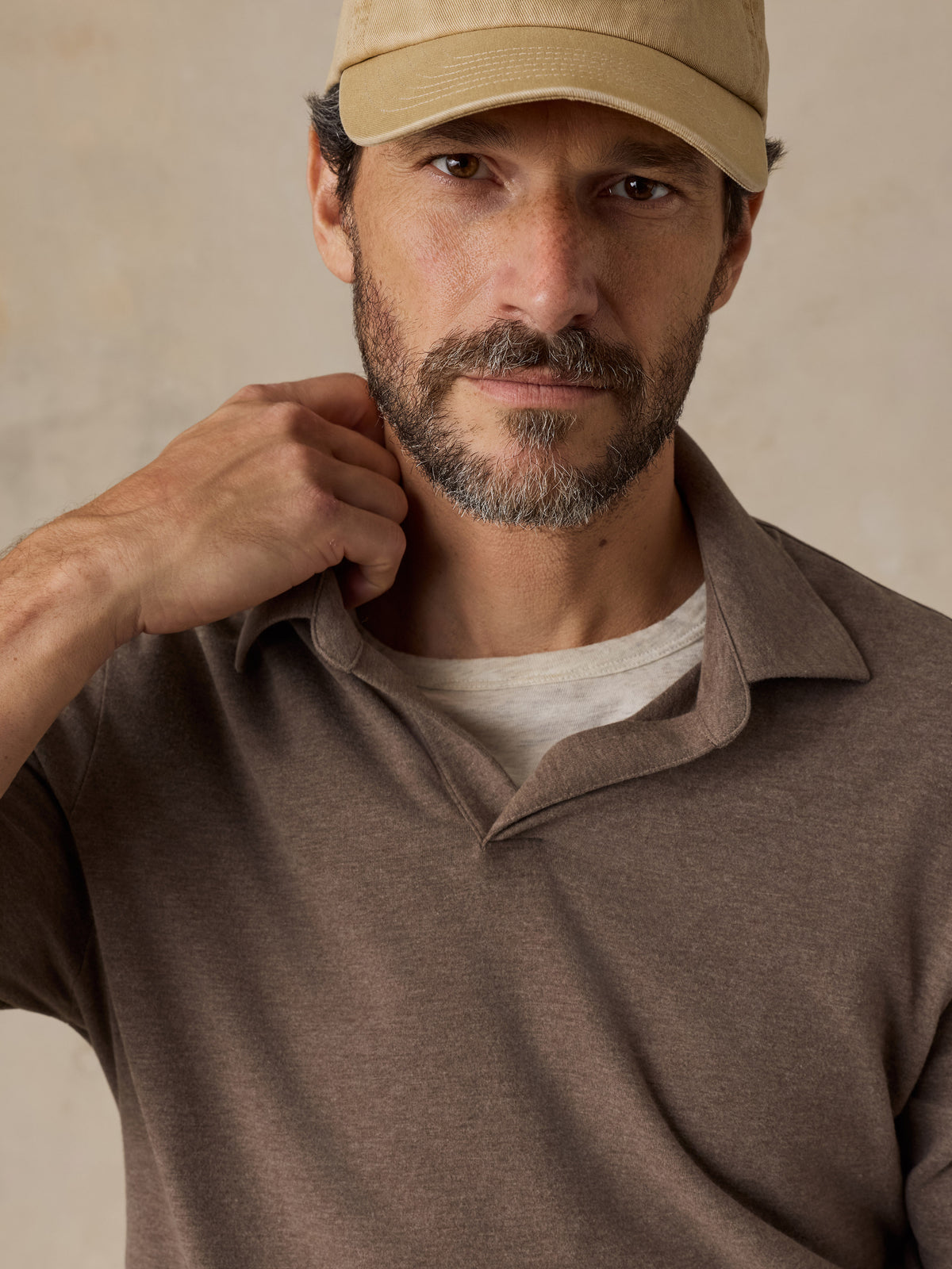 Close up of a man wearing a brown polo shirt and beige chino pants, image 3 of 6