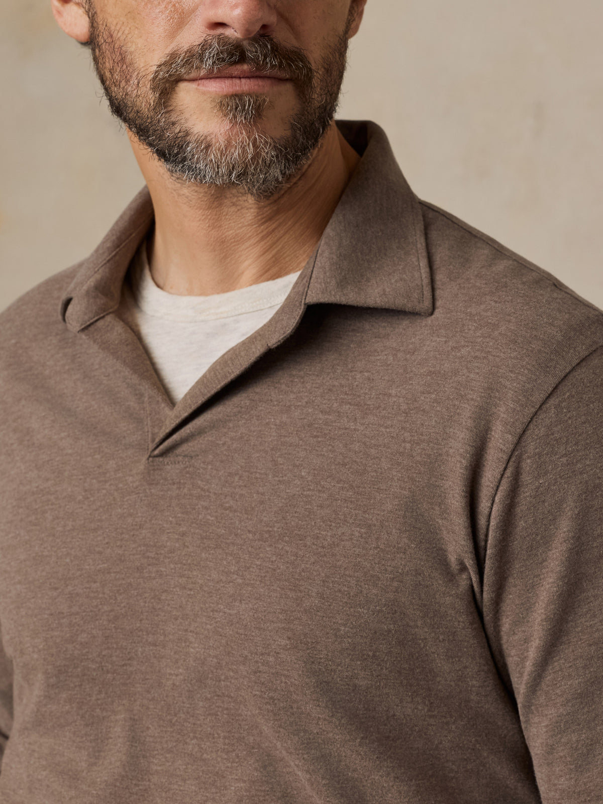 Close up of a man wearing a brown polo shirt over a white tee, image 5 of 6