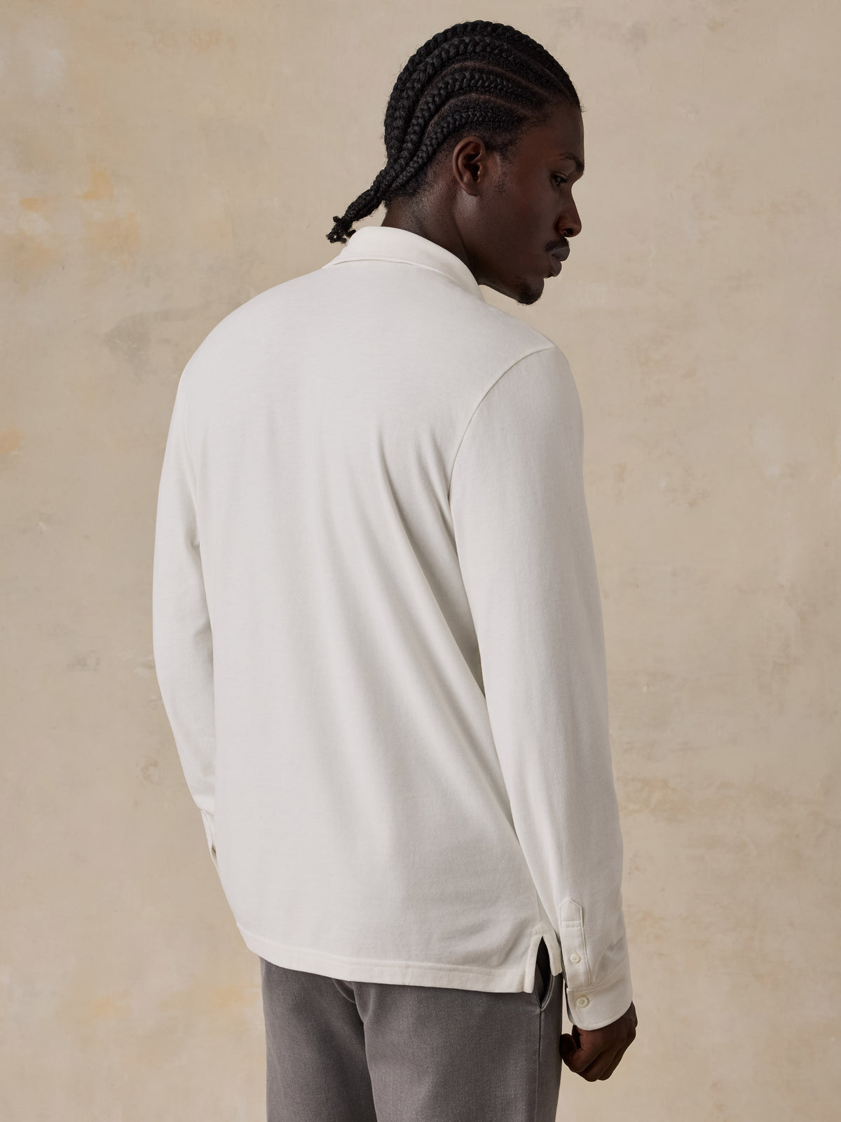 A man viewed from the back wearing a white long sleeve polo and grey pants, image 4 of 6