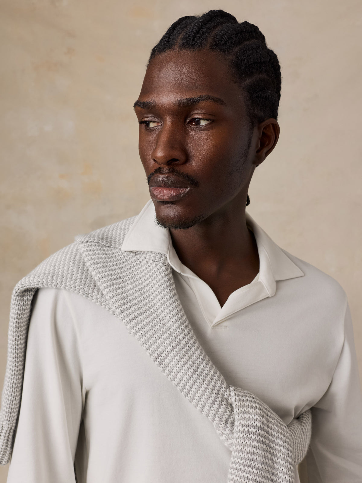 Close up of a man wearing a white long sleeve polo with a grey and white knit sweater, image 6 of 6