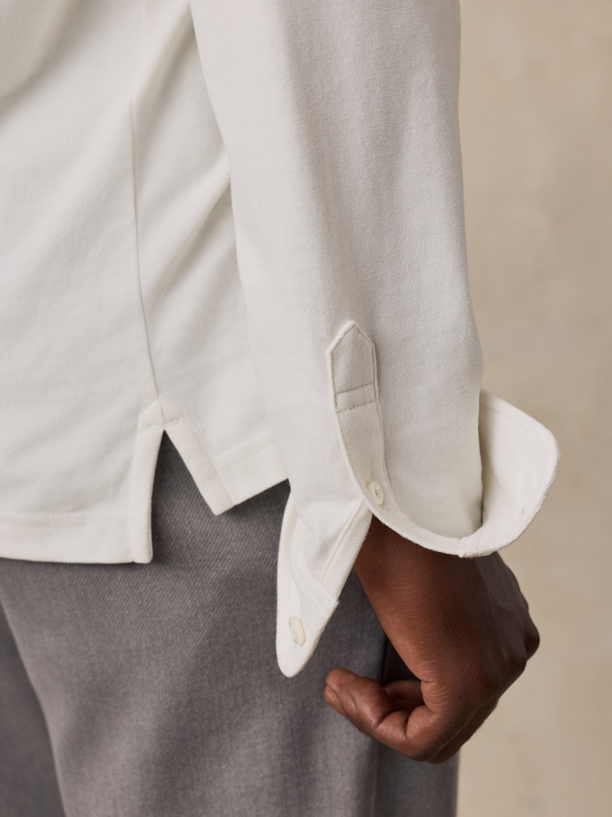 Close up of a man wearing a white long sleeve polo and grey pants, image 5 of 6