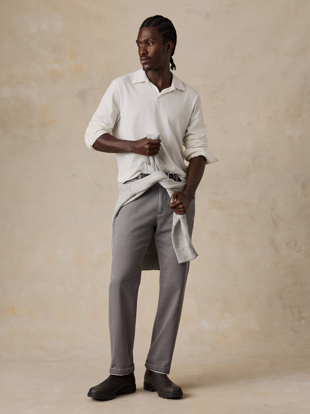 A man wearing a white long sleeve polo and grey pants, image 1 of 6