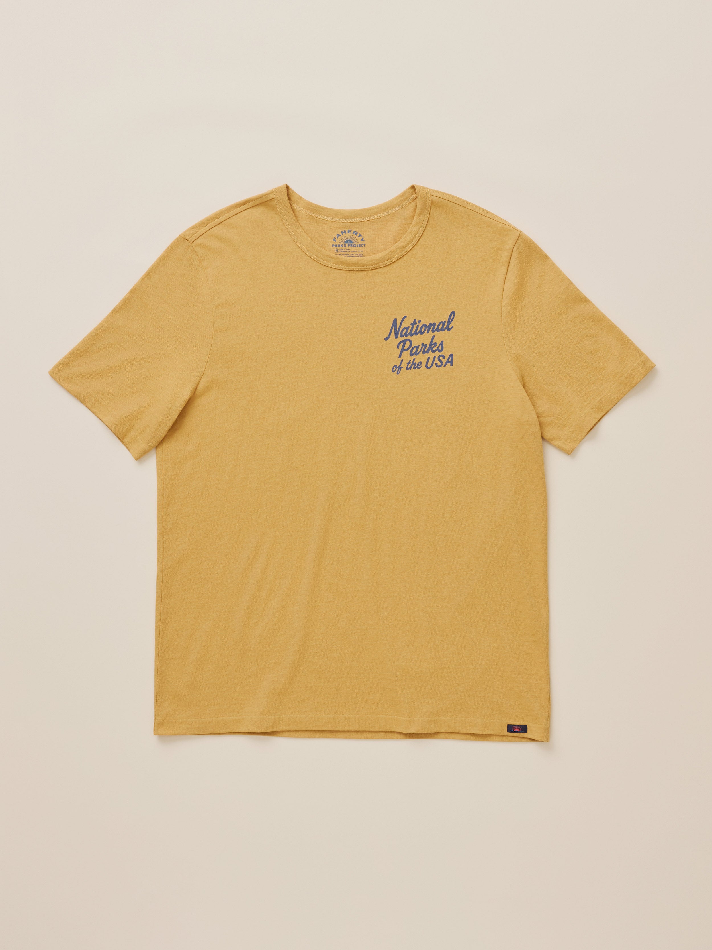 A yellow National Parks tee against a warm beige studio background