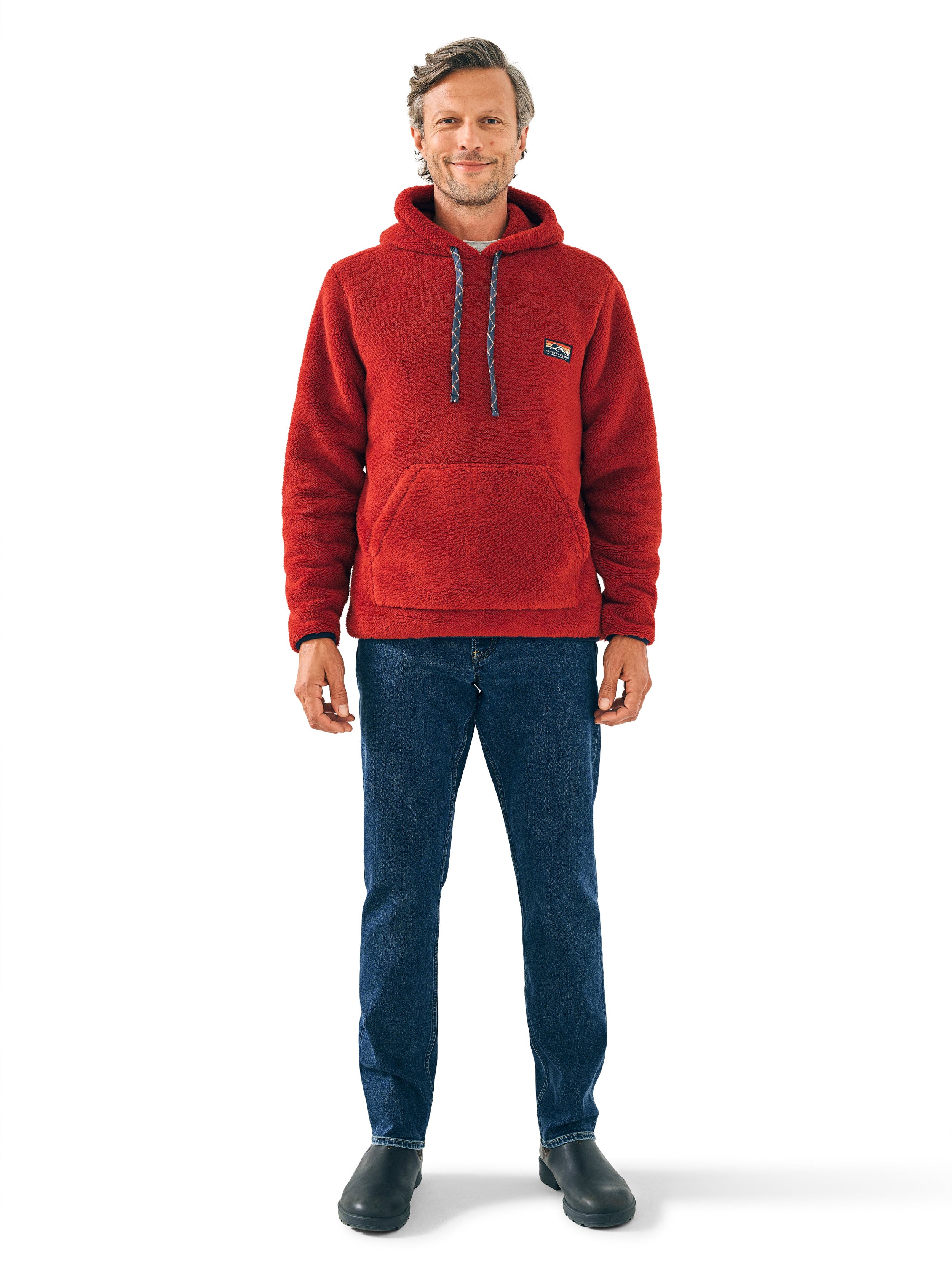 A man wearing a red hoodie and blue jeans