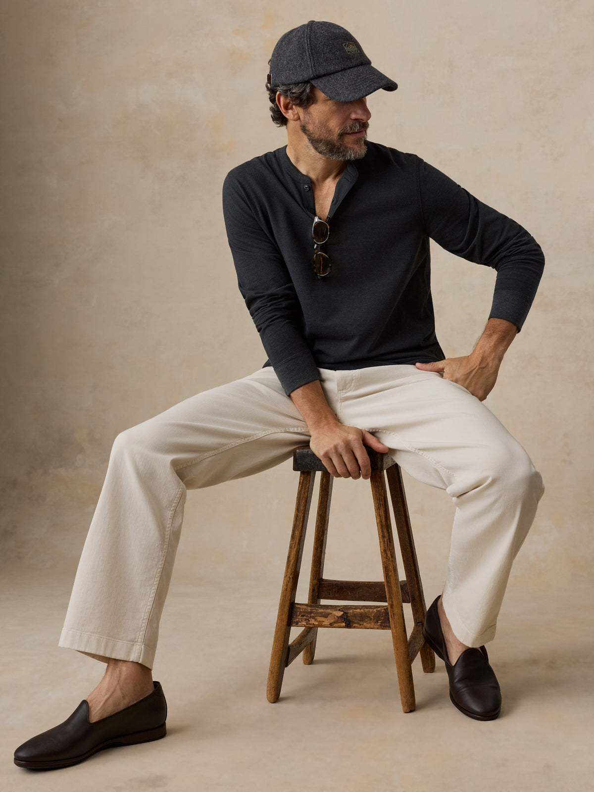 A man wearing a black henley and chino pants, image 5 of 6