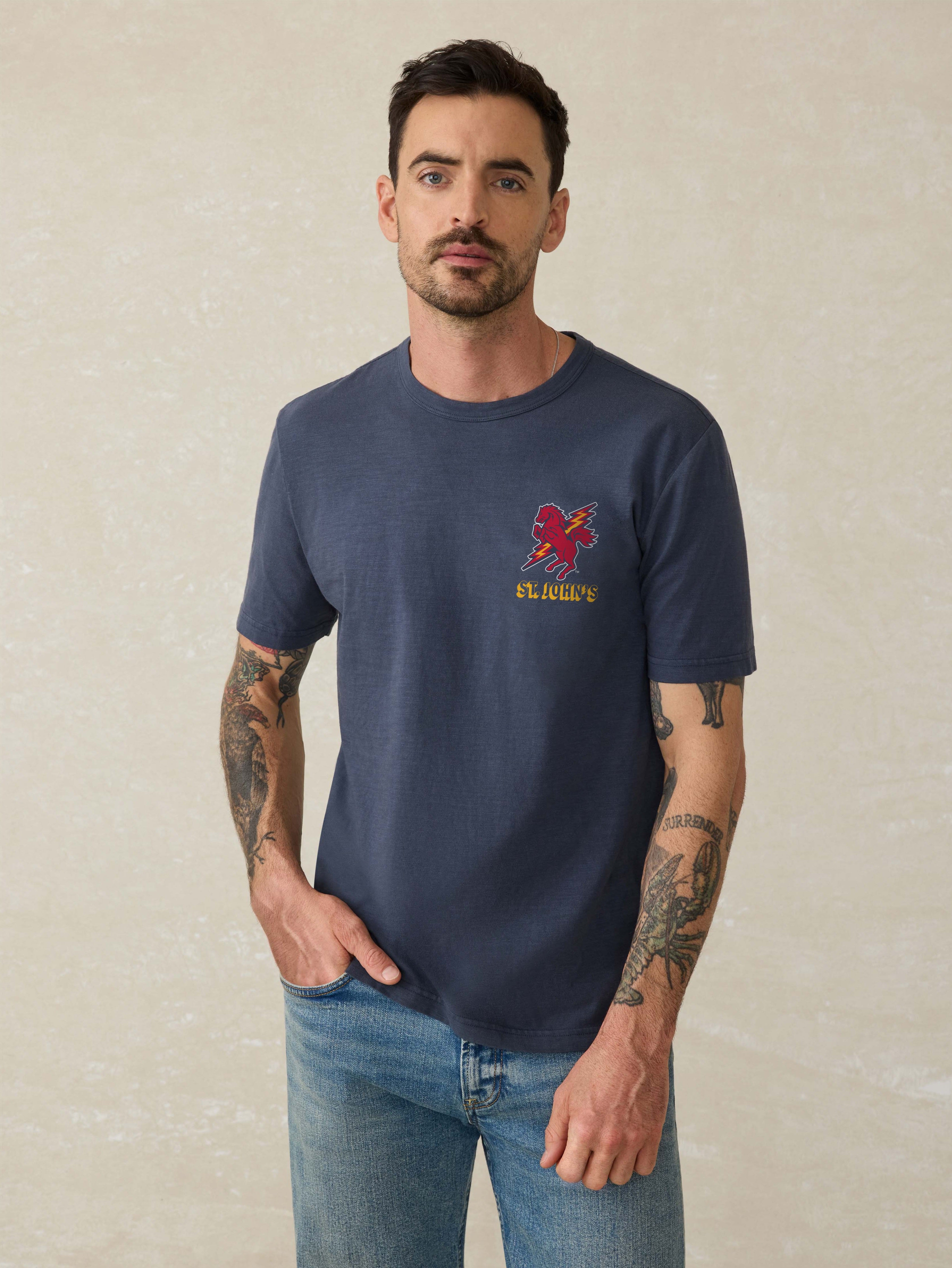 Man wearing a navy blue crew neck t-shirt with a short-sleeve design. The t-shirt has a St. John's graphic print on the front left chest