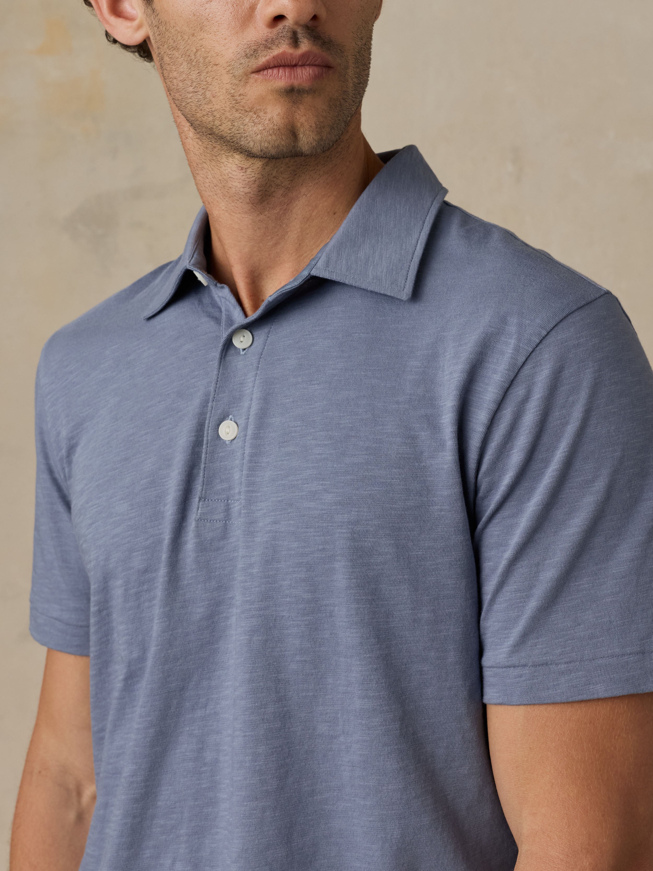 Man wearing a blue polo shirt against a beige background