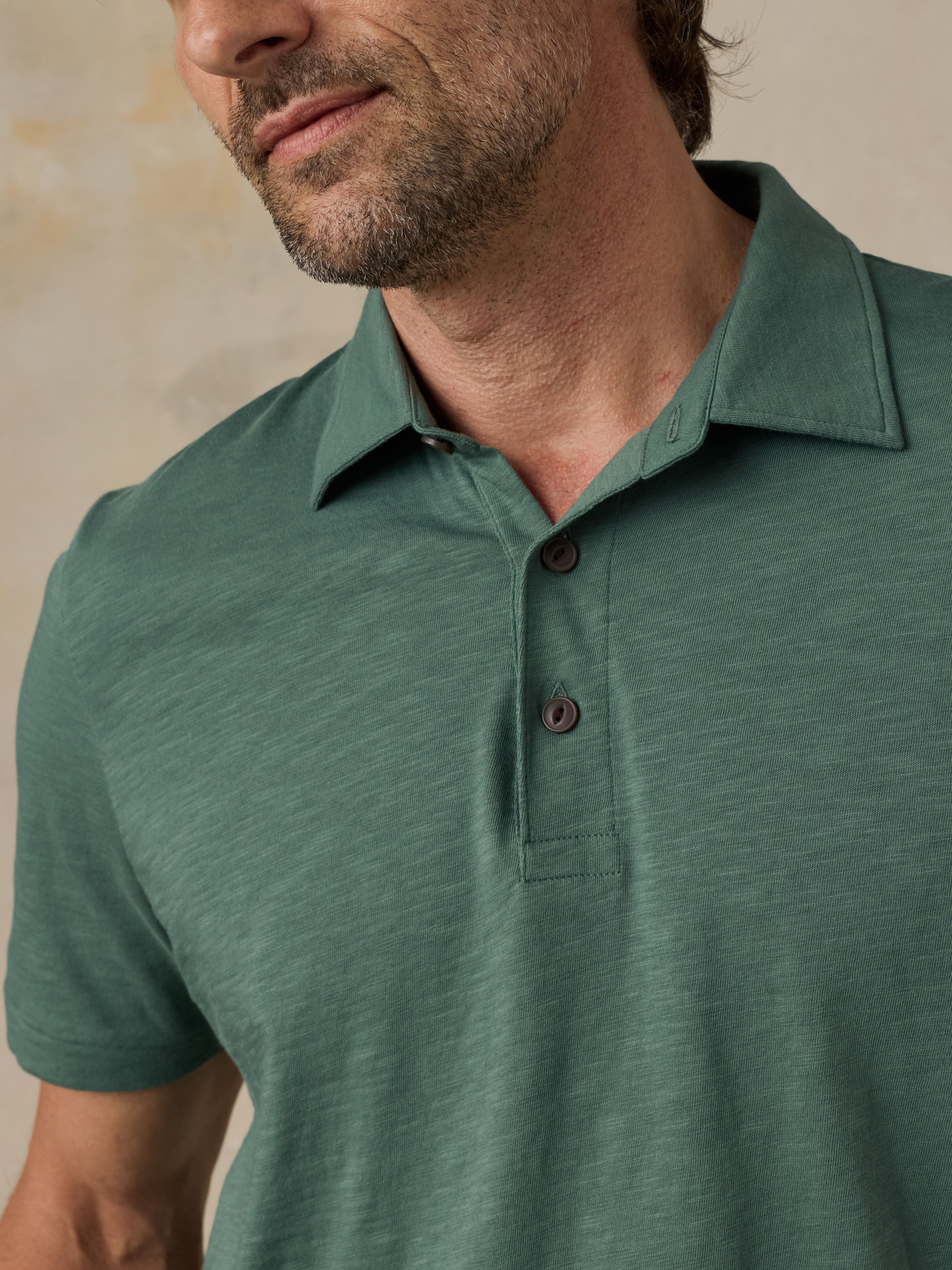 Man wearing a green polo shirt against a beige background
