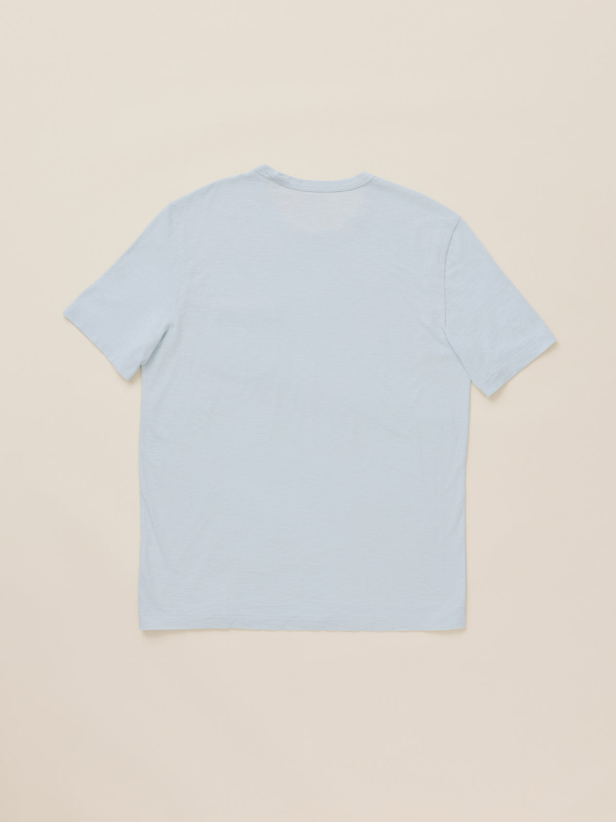 A light blue short-sleeve crewneck t-shirt shown from the back, laid flat against a solid beige background., image 2 of 2