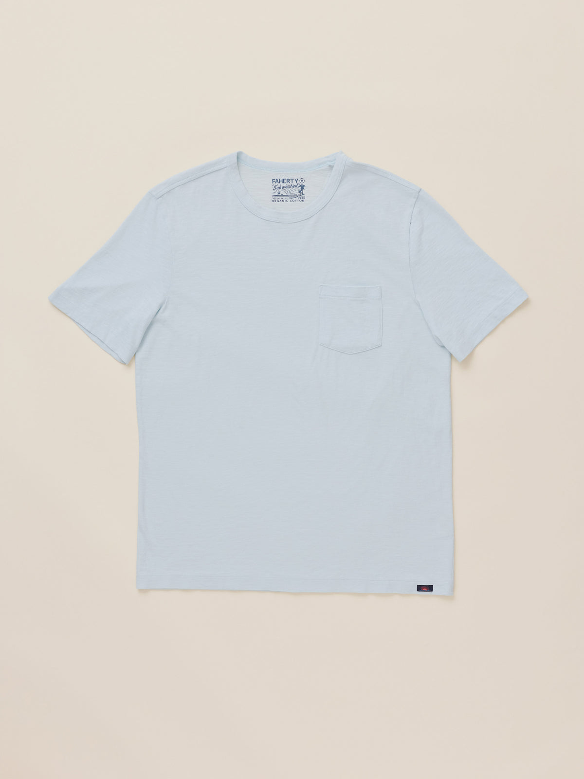 A light blue crewneck pocket t-shirt laid flat against a solid beige background., image 1 of 2