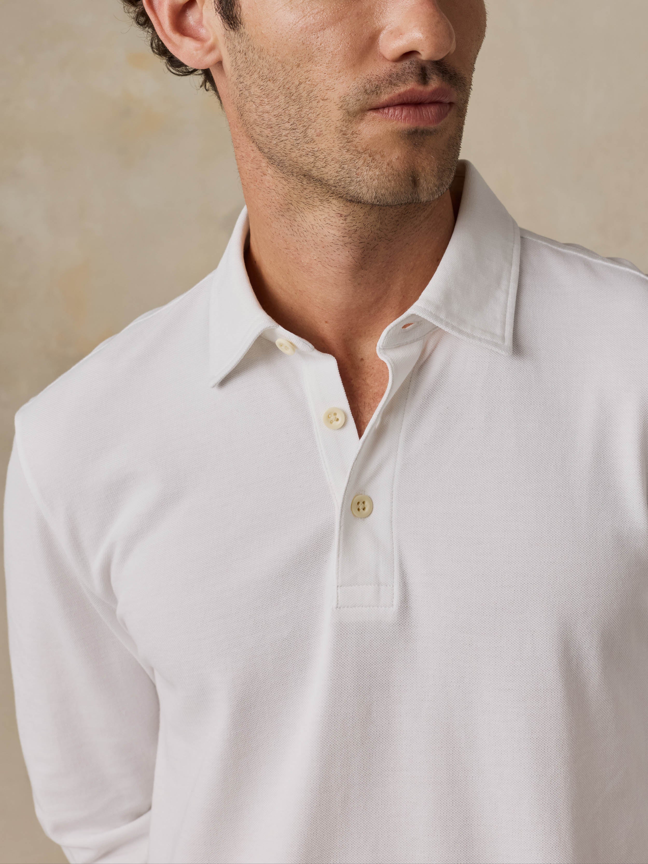 Man wearing a white long-sleeve shirt against a beige background