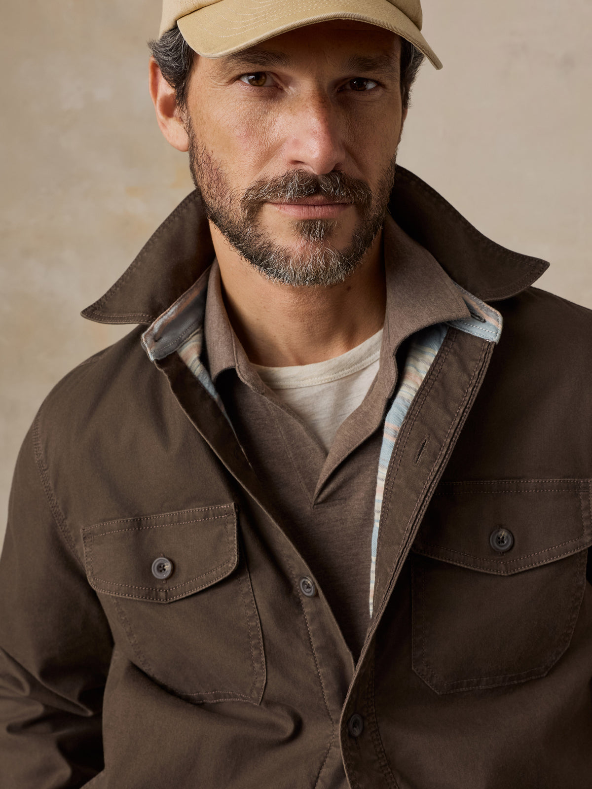 Close up of a man wearing a brown jacket over a brown polo, image 3 of 5