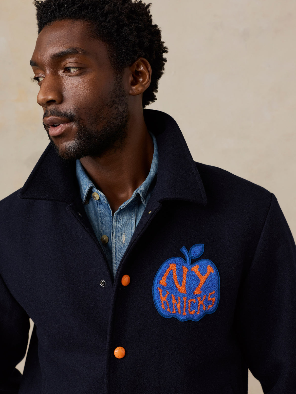 Close up of a man wearing a NY Knicks varsity jacket, image 5 of 8