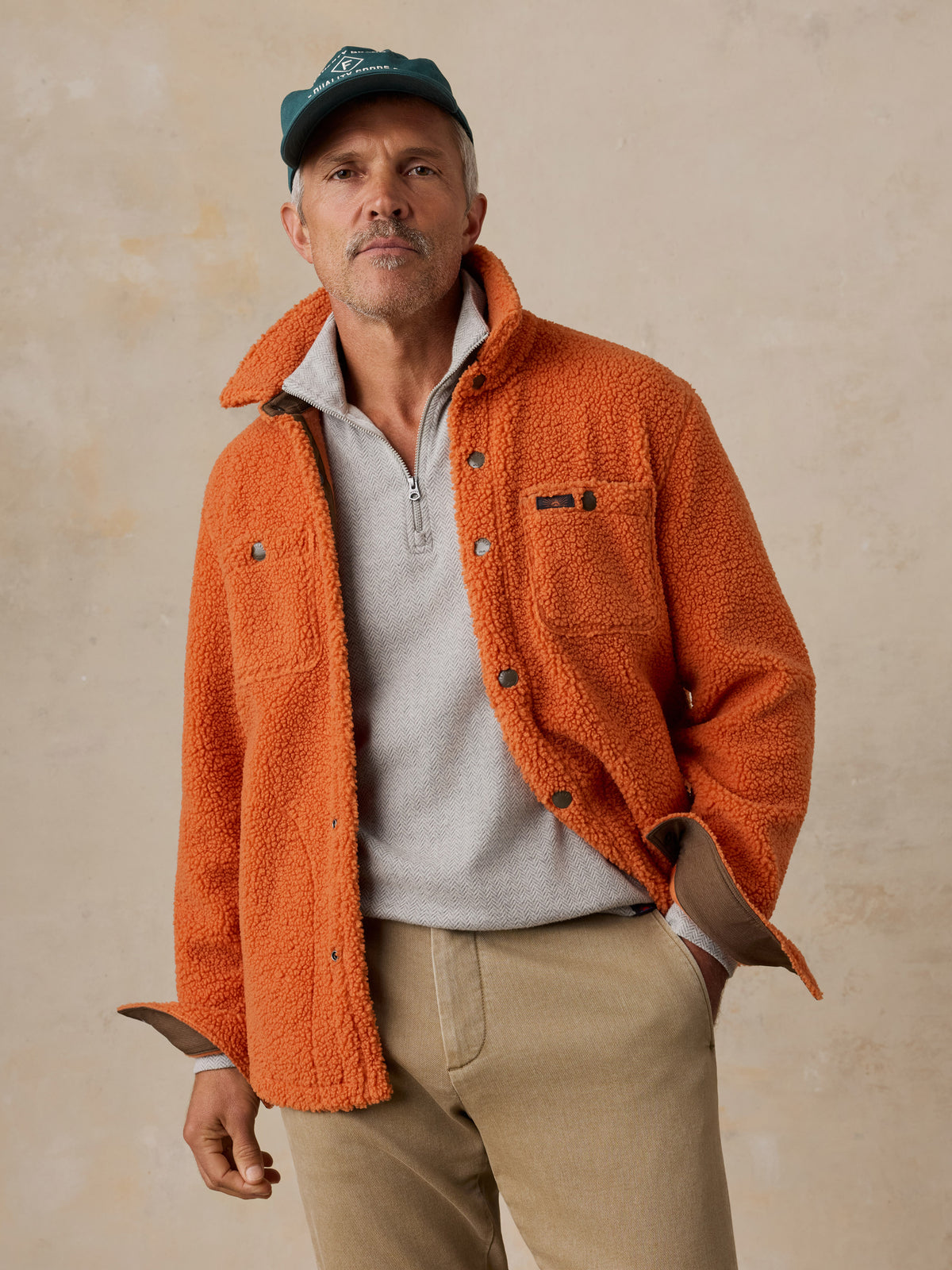 A man wearing an orange fleece and chino pants, image 2 of 6